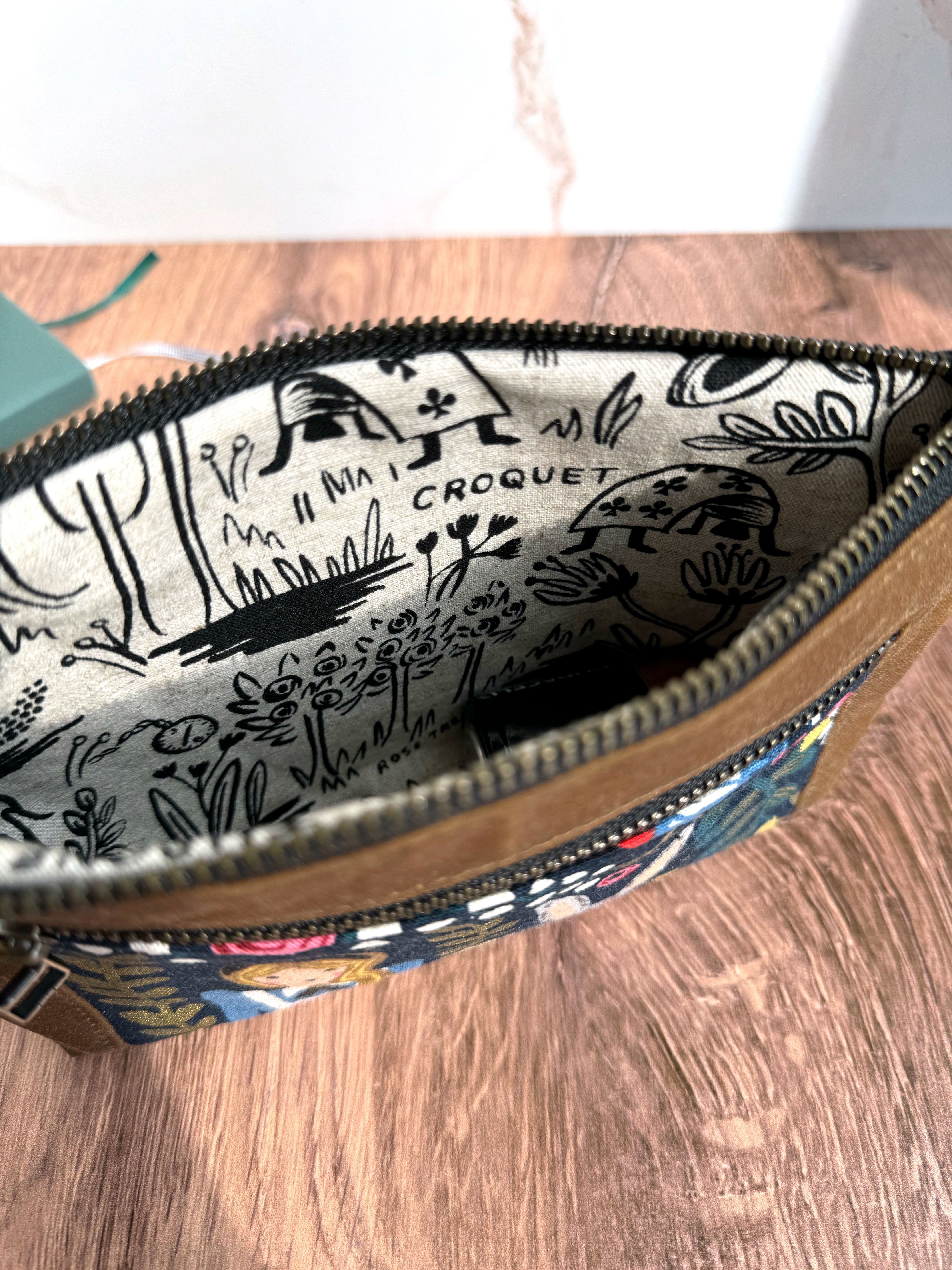 Open zipper on Alice in Wonderland pouch shows black and white lining fabric - more Alice themed canvas illustrations.