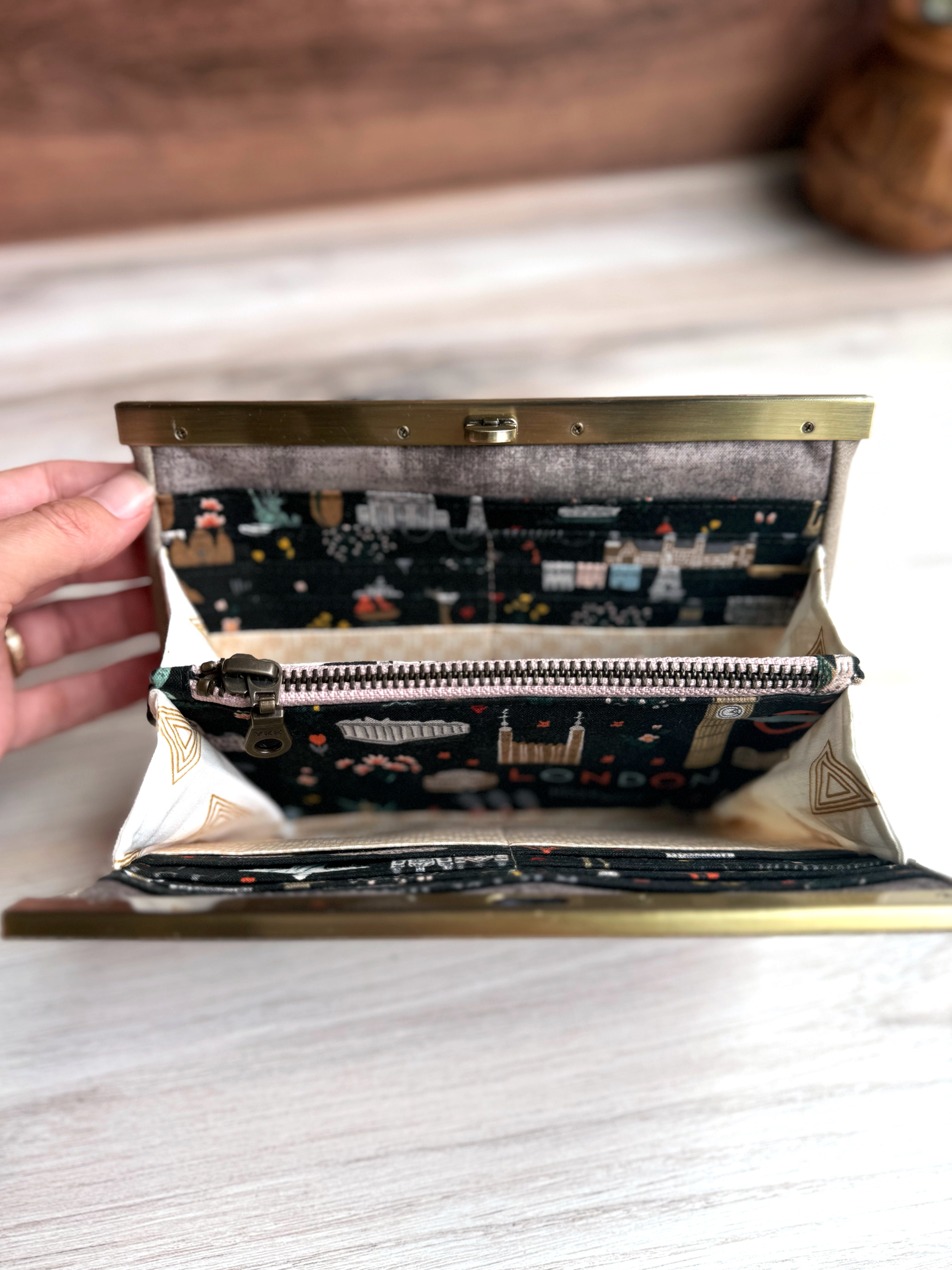 Gray/Tan accordion style wallet opened to show zipper pocket and fun illustrated Rifle Paper fabrics featuring iconic world images