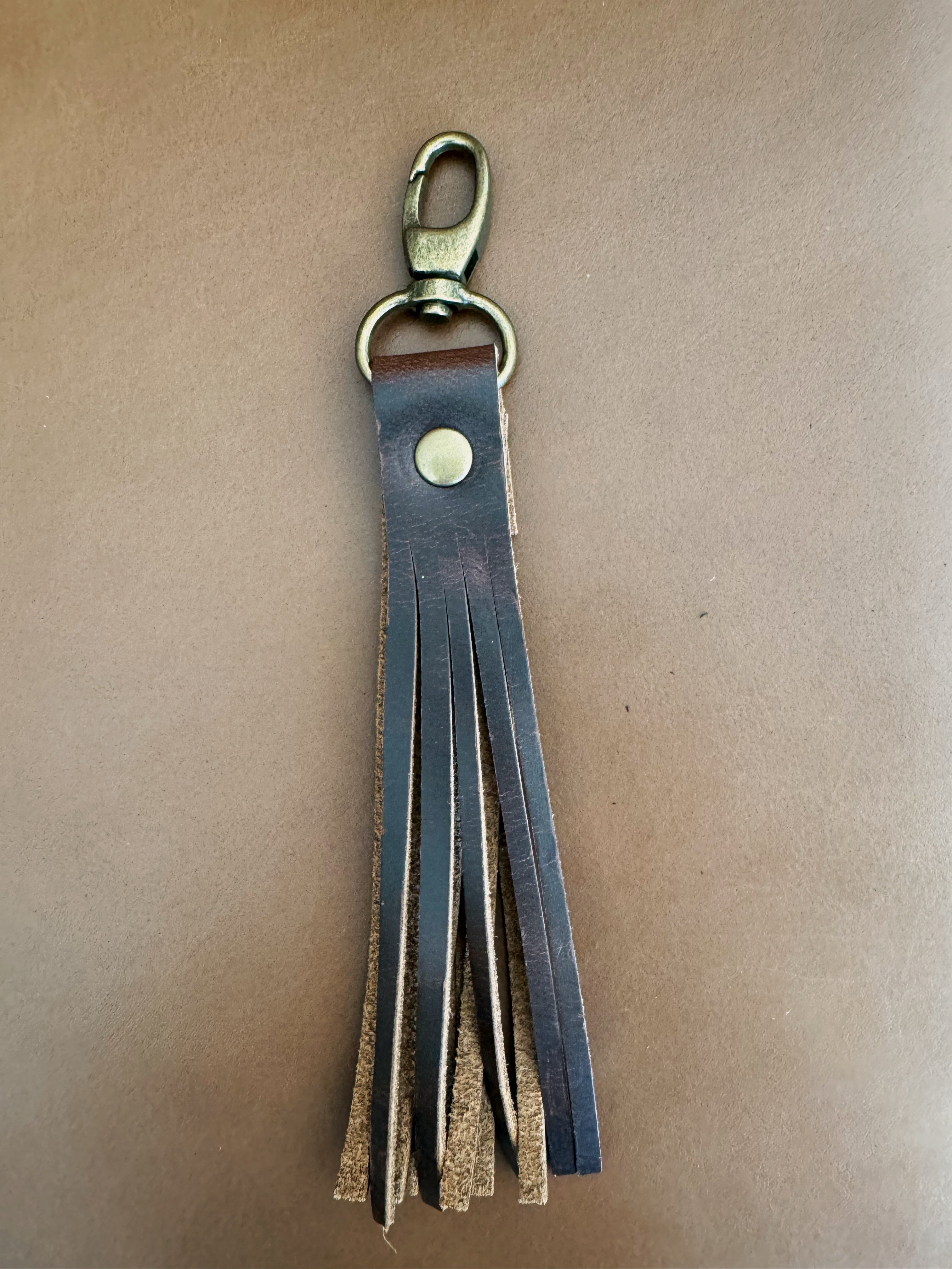 Tassel with brown leather fringe and antique brass hardware. Lobster clasp easily attaches to bags and accessories.