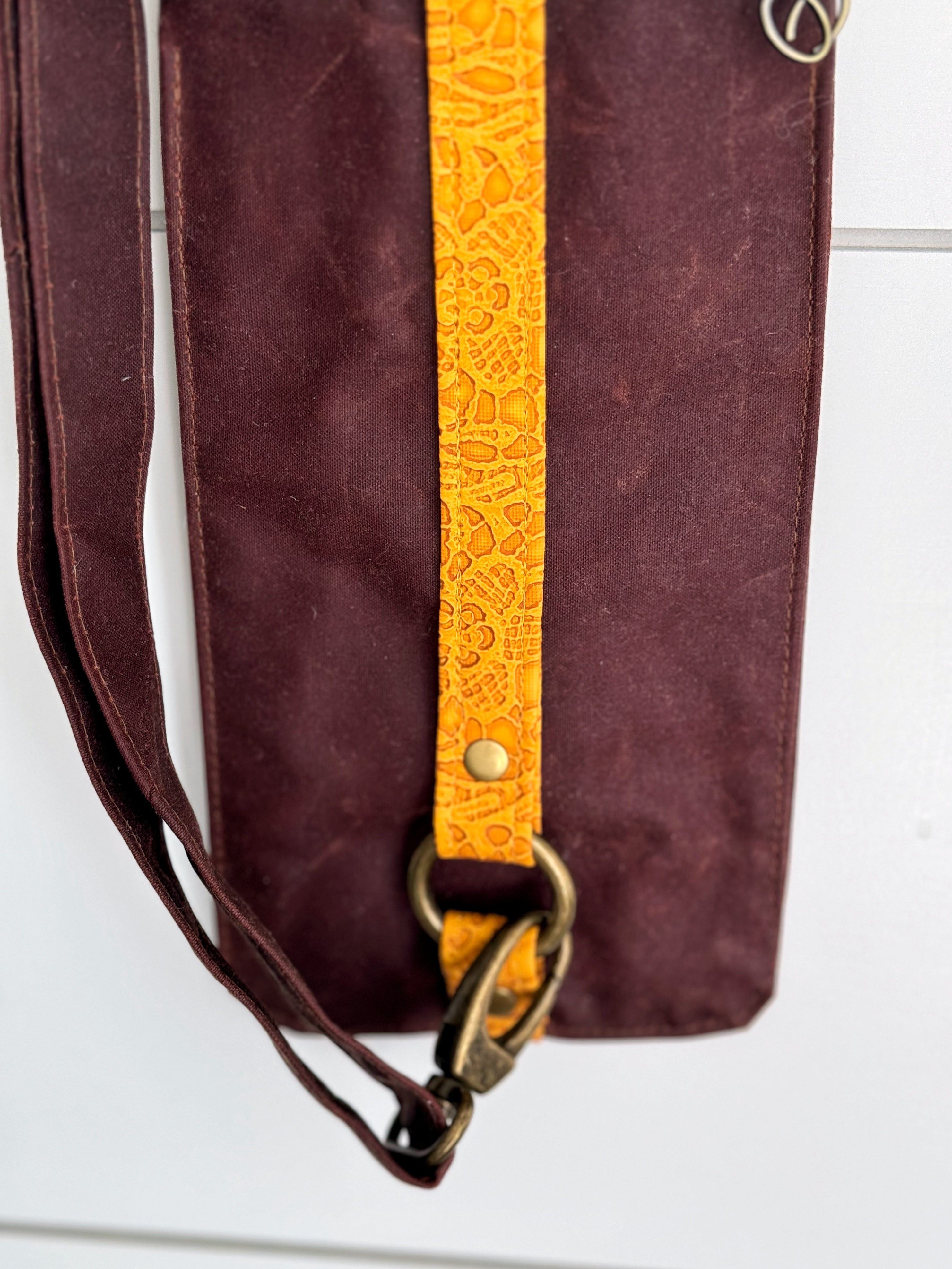 Bottom of Ella bag shows swivel clasp attaching to brass circle ring held in place with yellow lace vinyl trim.