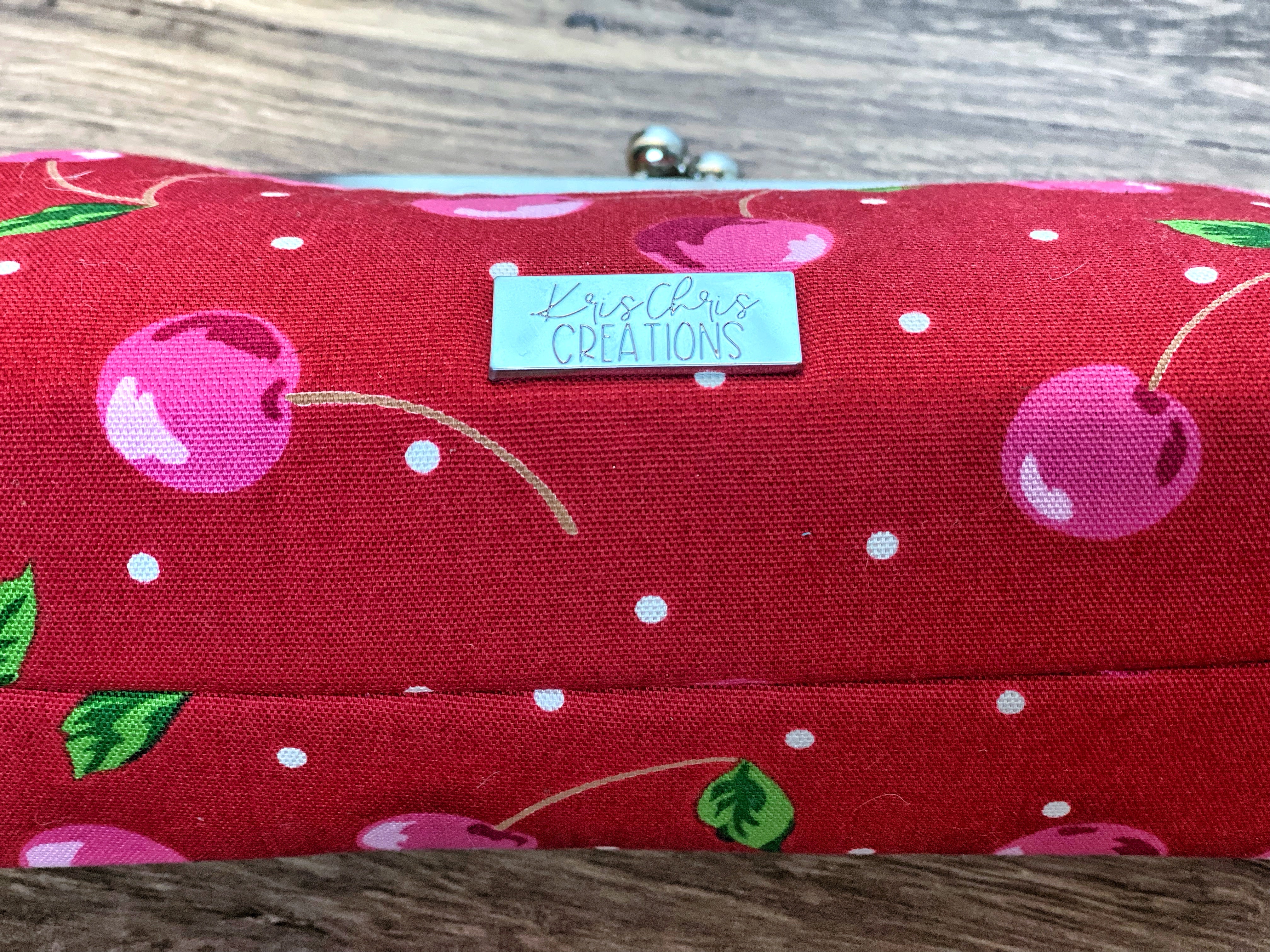 Bottom view of cherry kisslock bag to show close view of fabric and silver KrisChris tag.