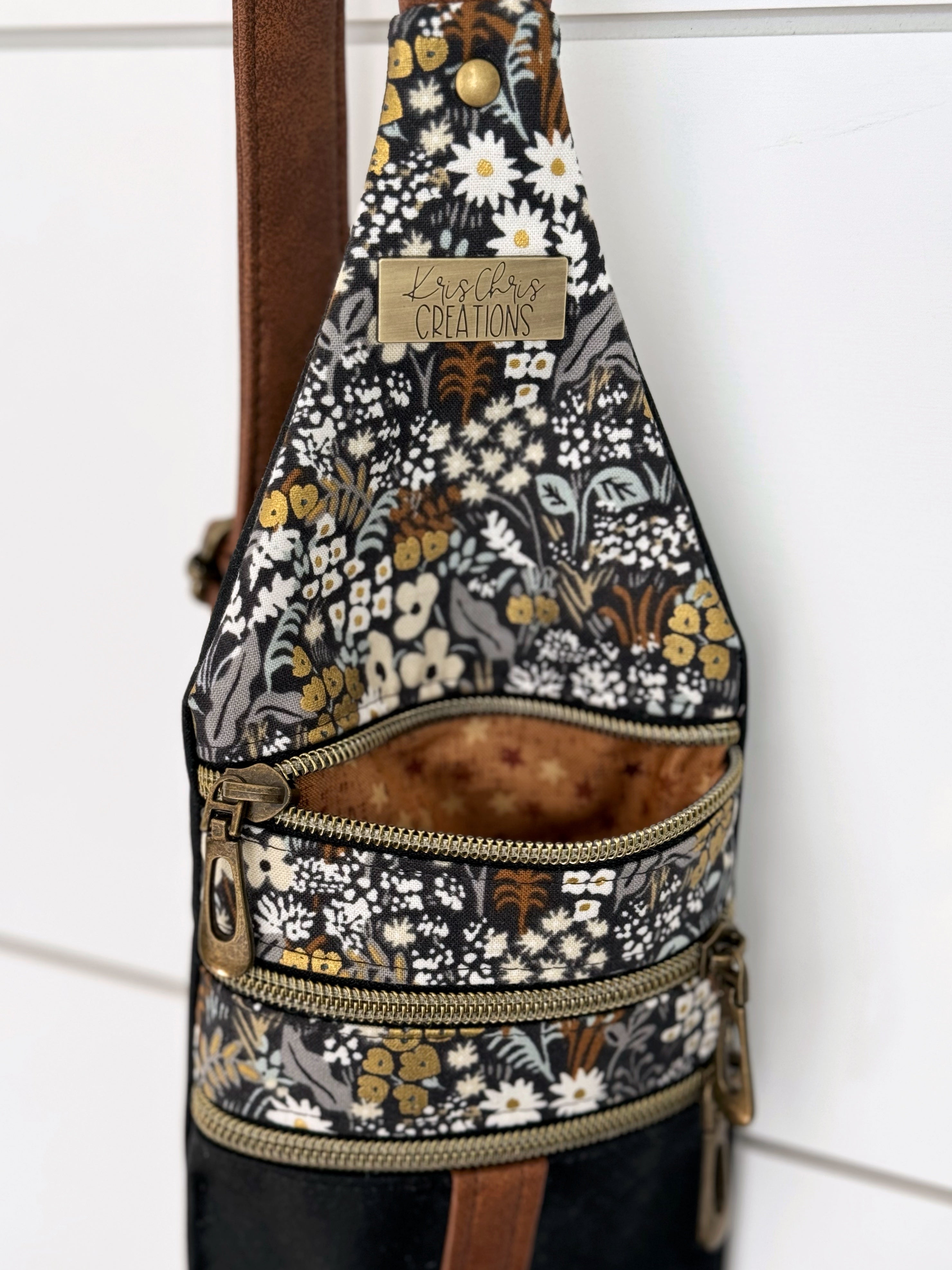 Top of floral crossbody bag shows top zipper pocket opened with brown star fabric inside.