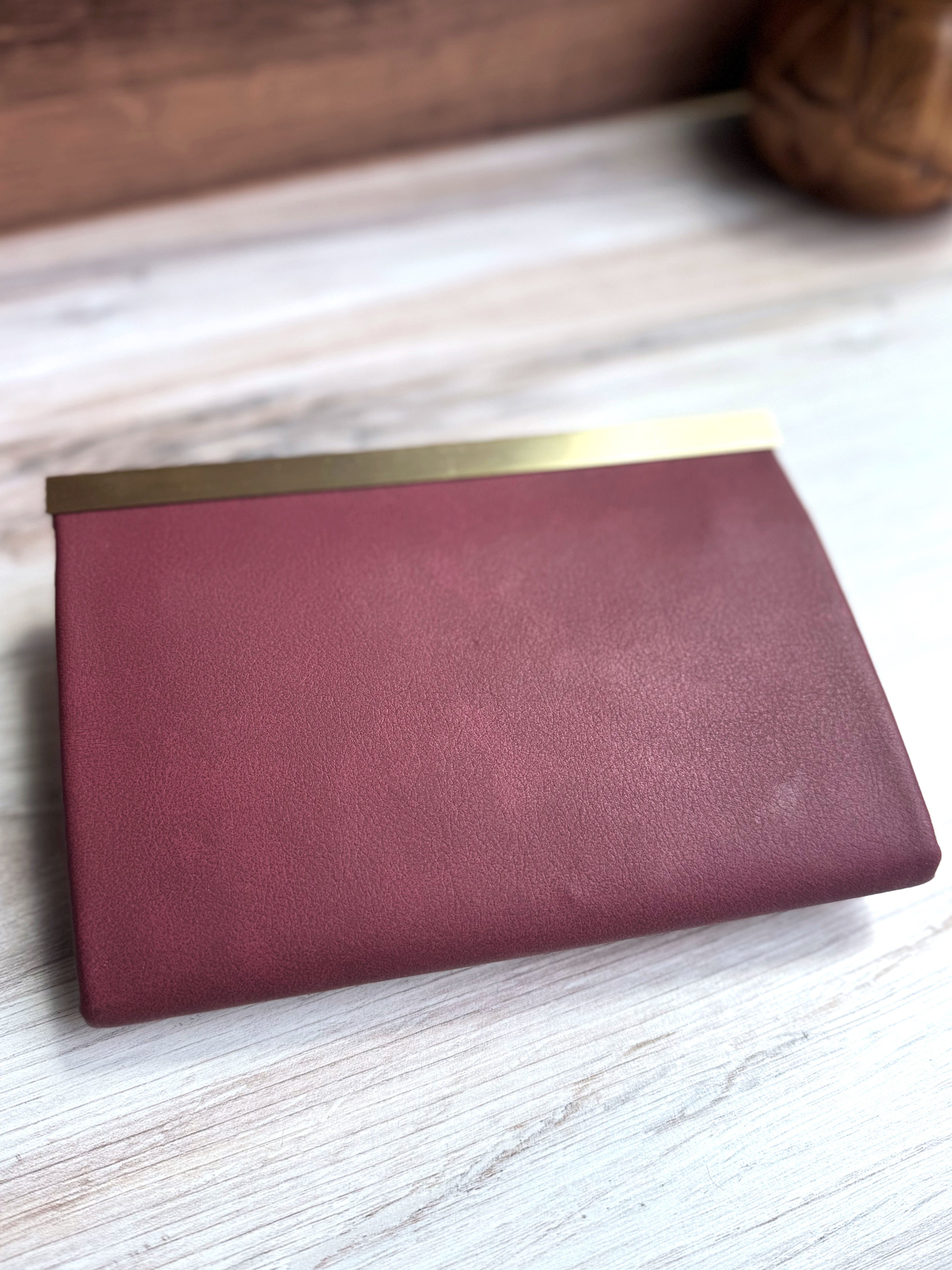 Rear view of Wine colored wallet in vegan leather (vinyl) with antique brass closure along top edge.