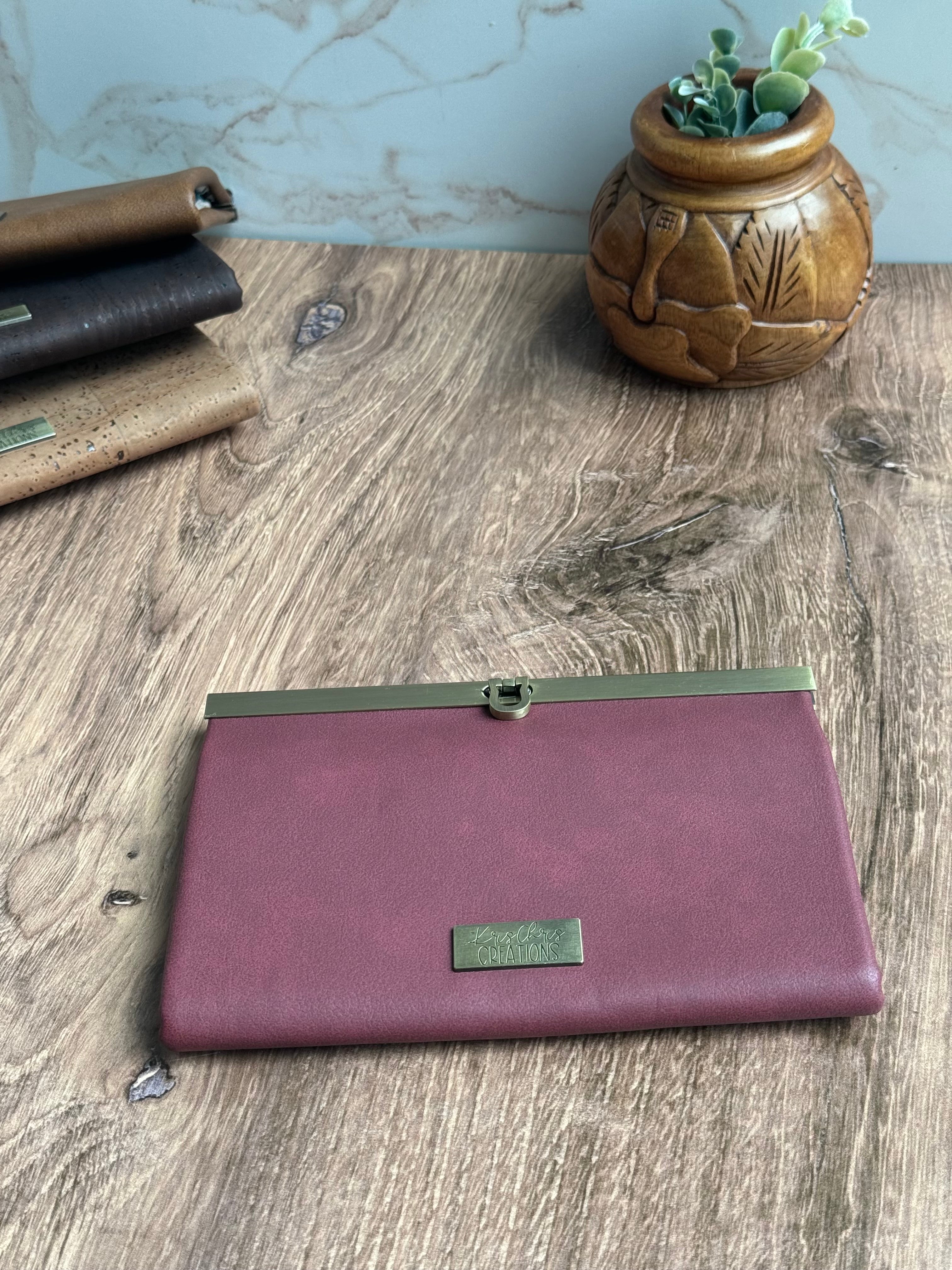 Faux leather accordion wallet with antique brass hardware along top edge in dark red/maroon.