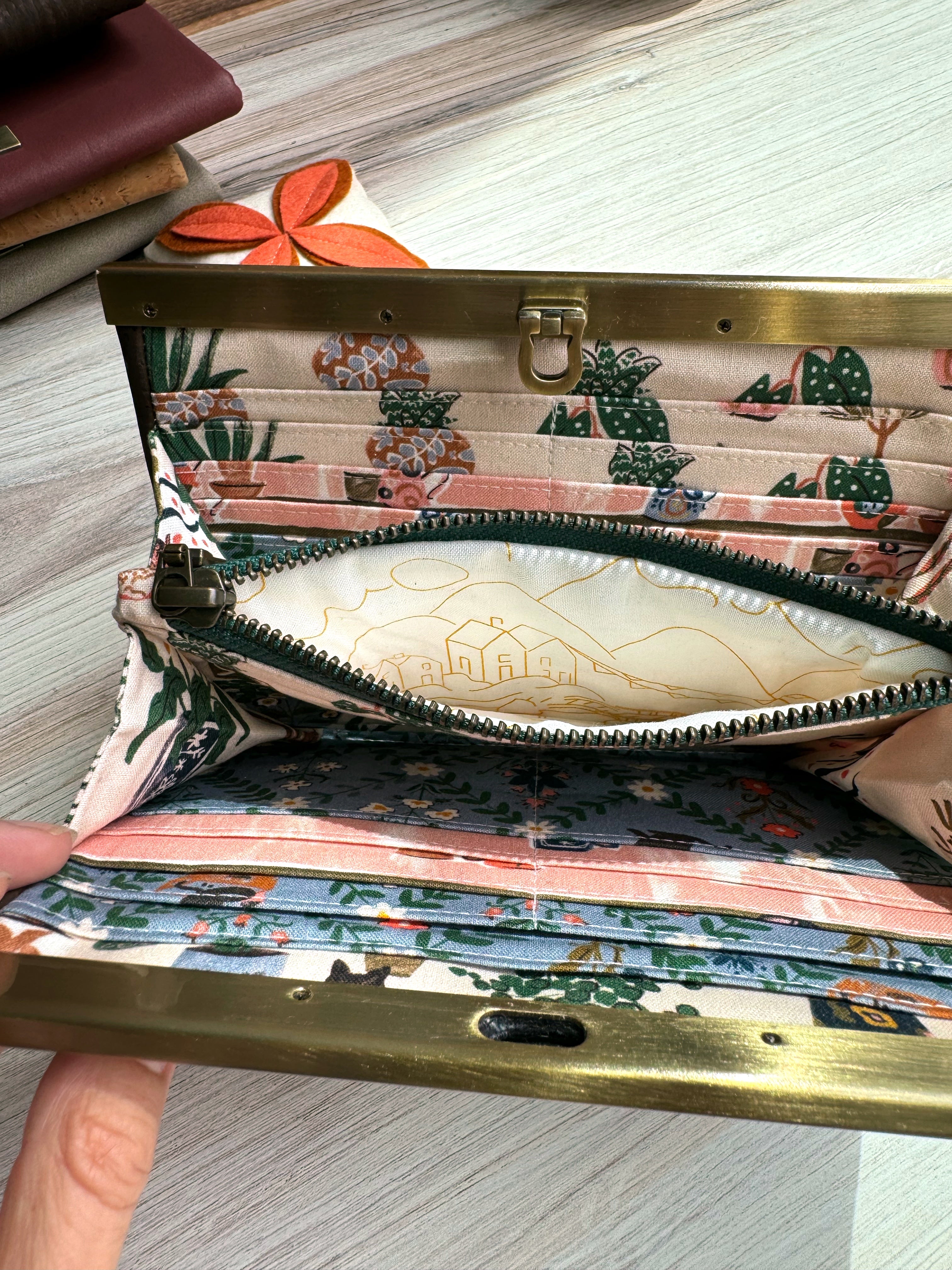 Accordion wallet with green zipper open to show house in country on fabric inside. Many card slots, and adorable fabrics throughout.