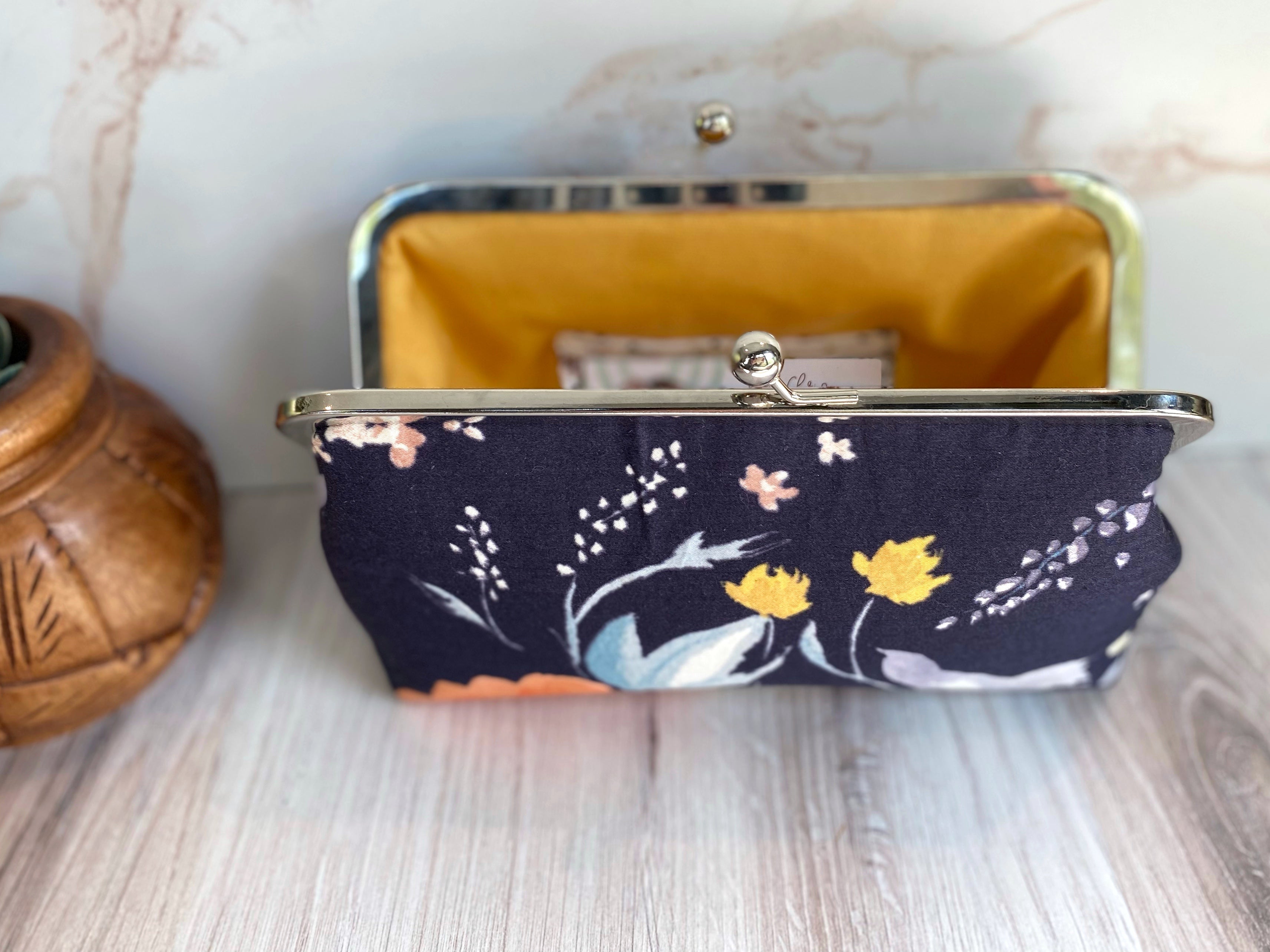 Opened floral navy kisslock clutch with yellow lining and Japanese watercolor fabric exterior