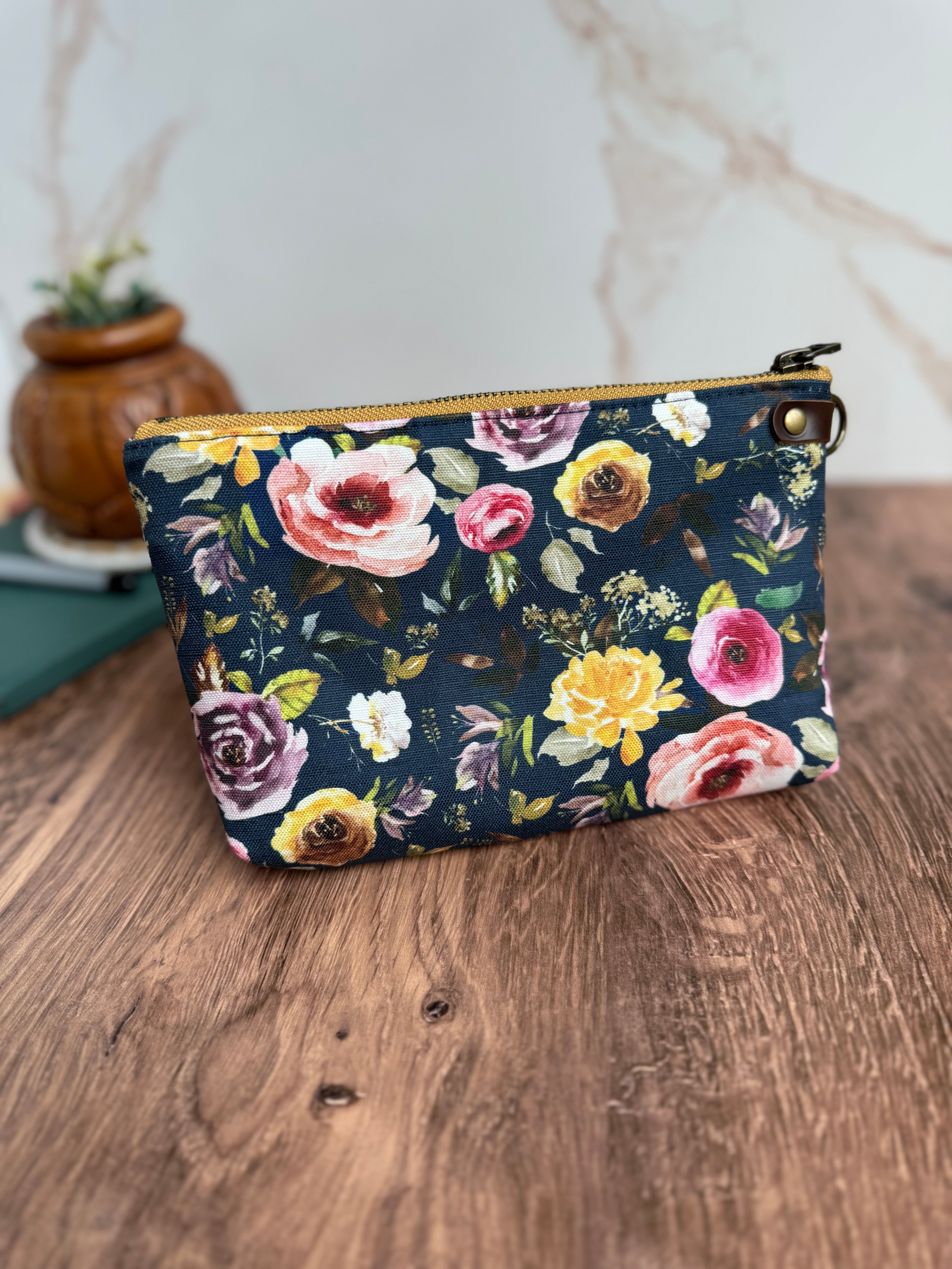 Bright floral fabric pouch. Fabric has navy background and yellow, pink, and purple roses.
