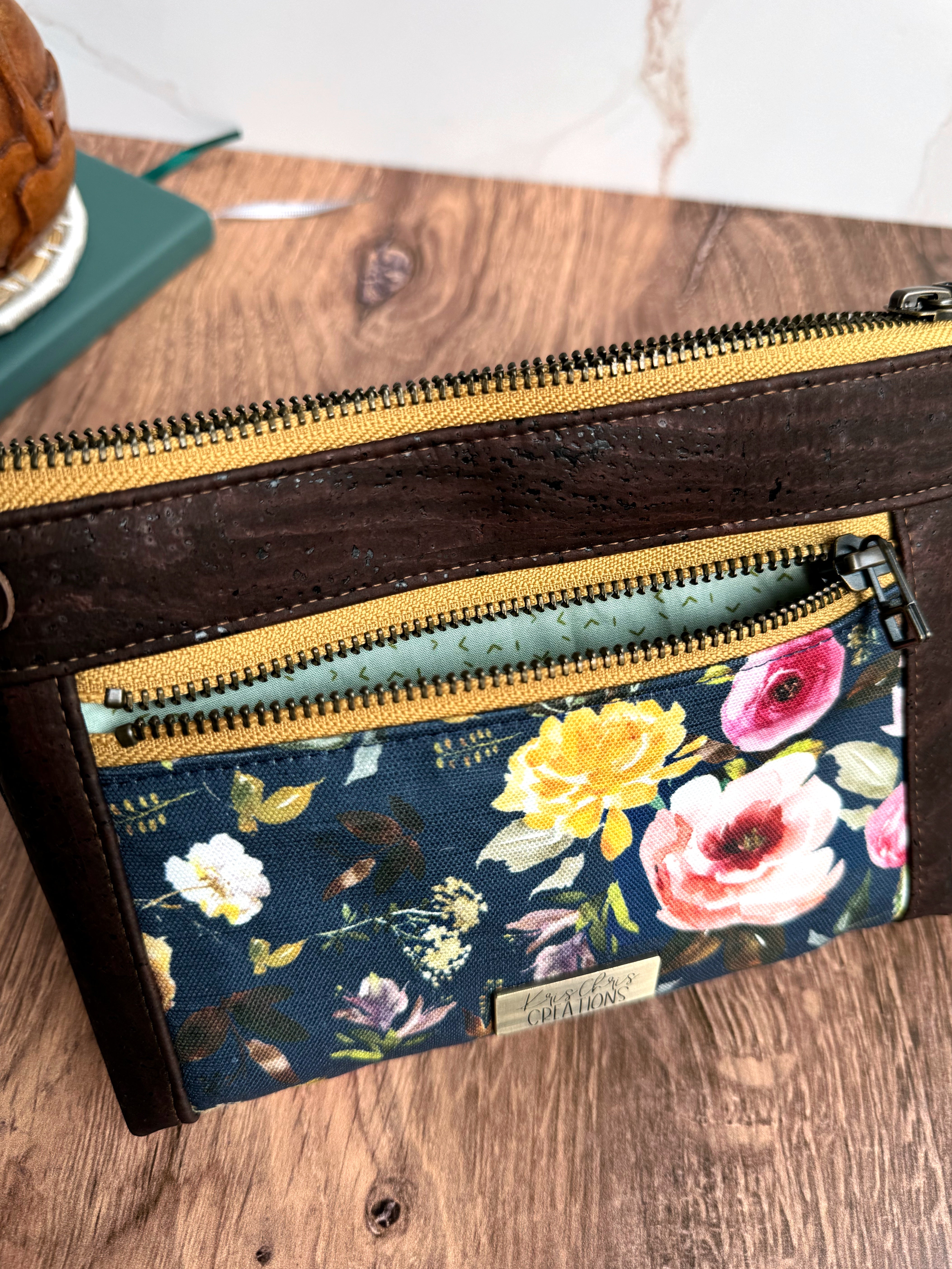 Floral pouch shows light teal lining fabric in small zipper pocket on wooden base and white marble background.