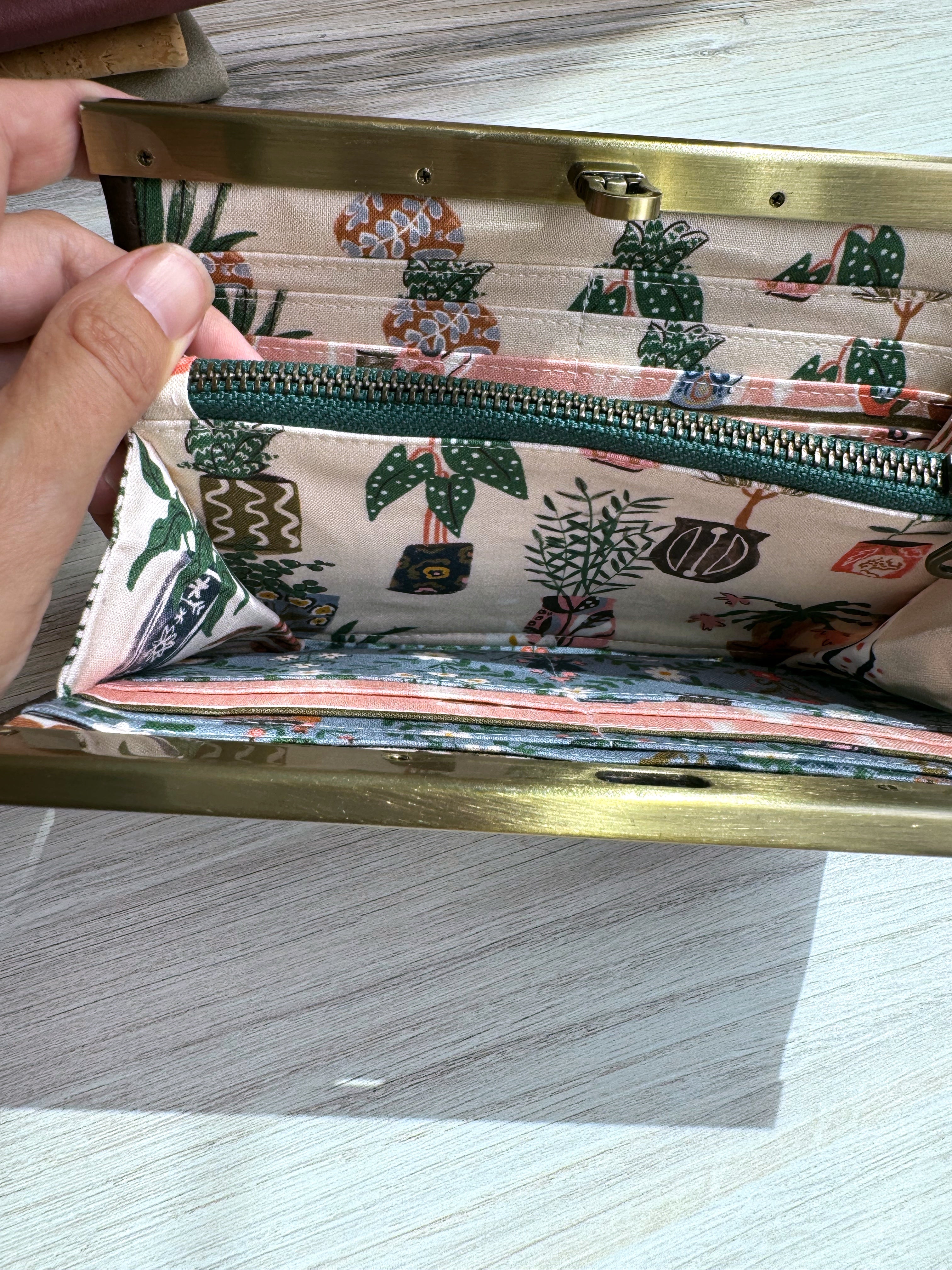 Accordion wallet with green zipper, many card slots, and adorable pink and blue fabric with variety of house plants.
