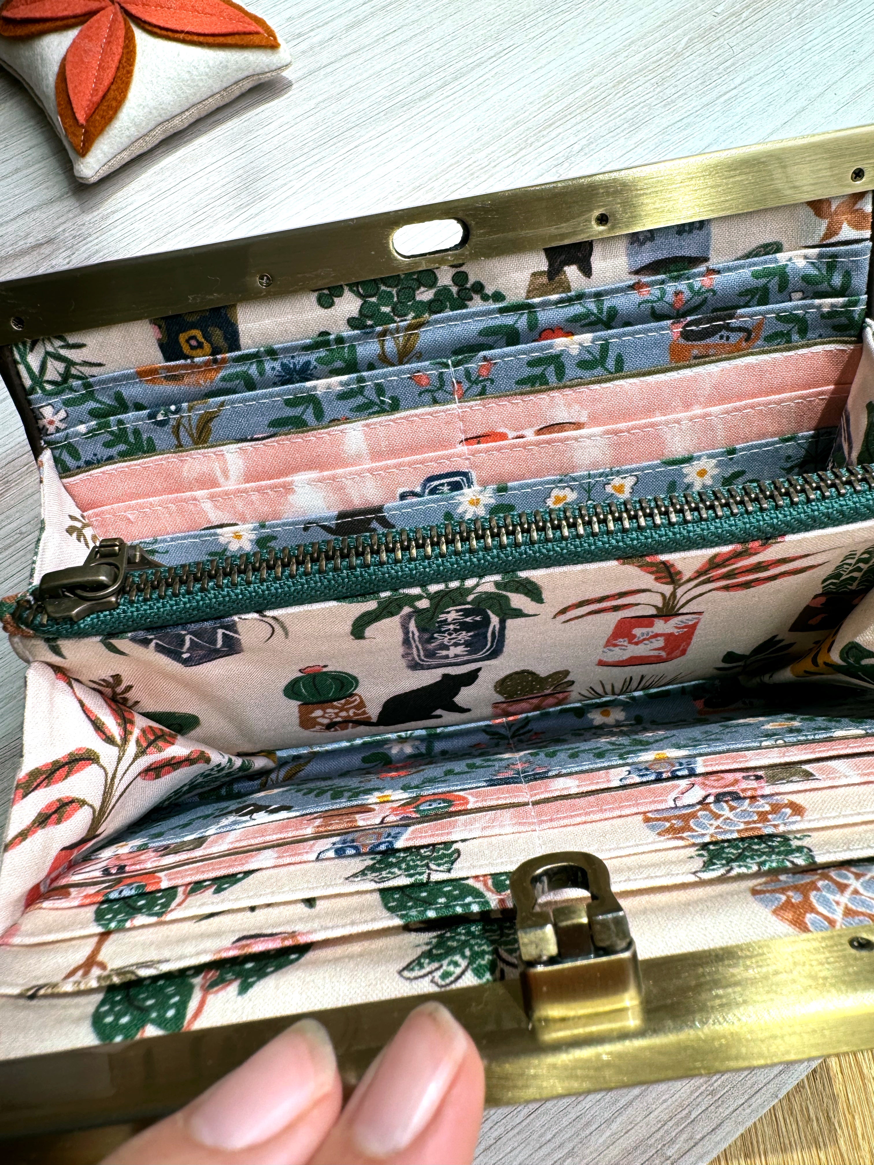 Accordion wallet with green zipper, many card slots, and adorable pink and blue fabric with house plants and black cats.