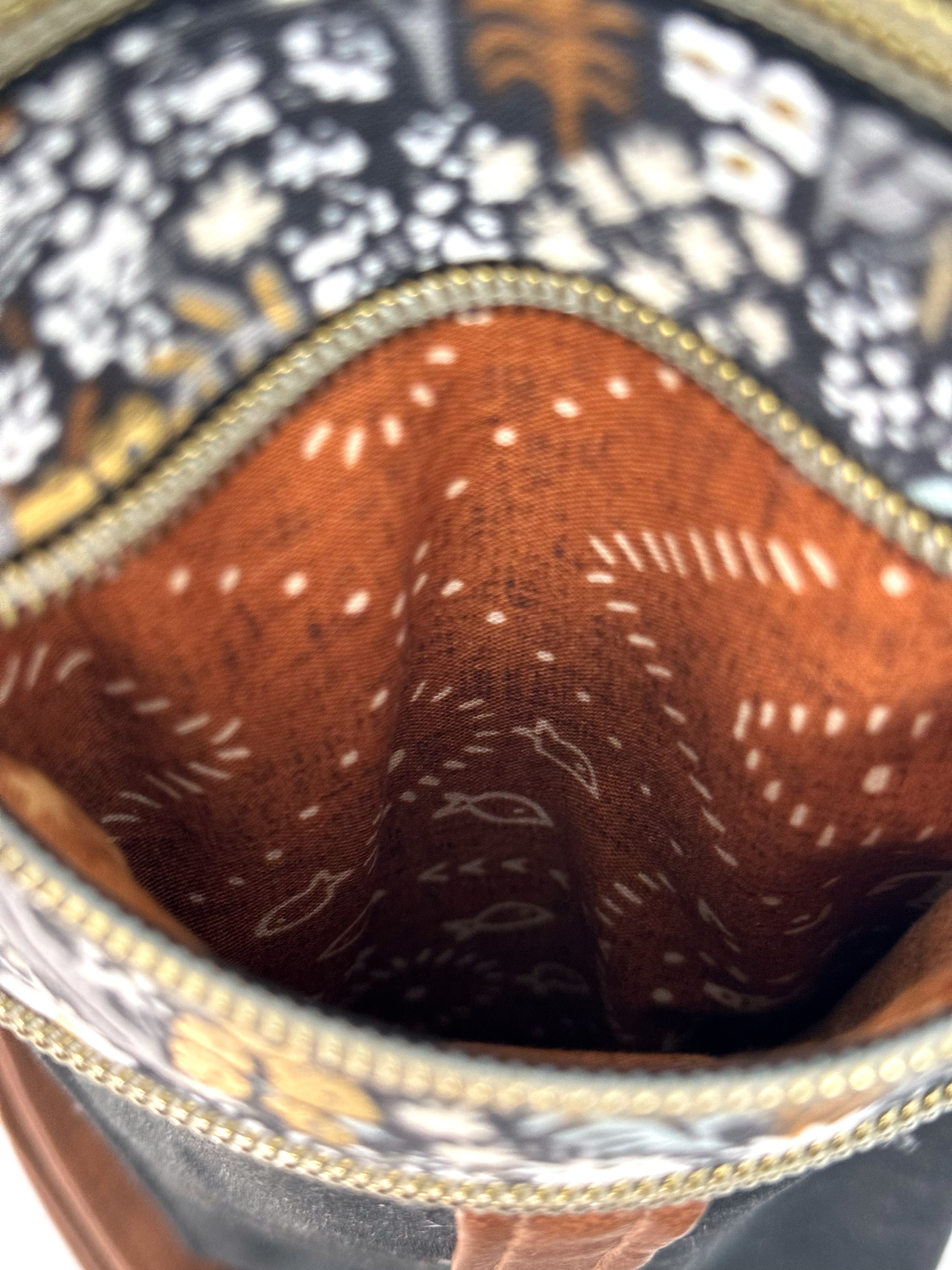 View inside one of the pockets of the crossbody bag reveals geometric brown design and little fish