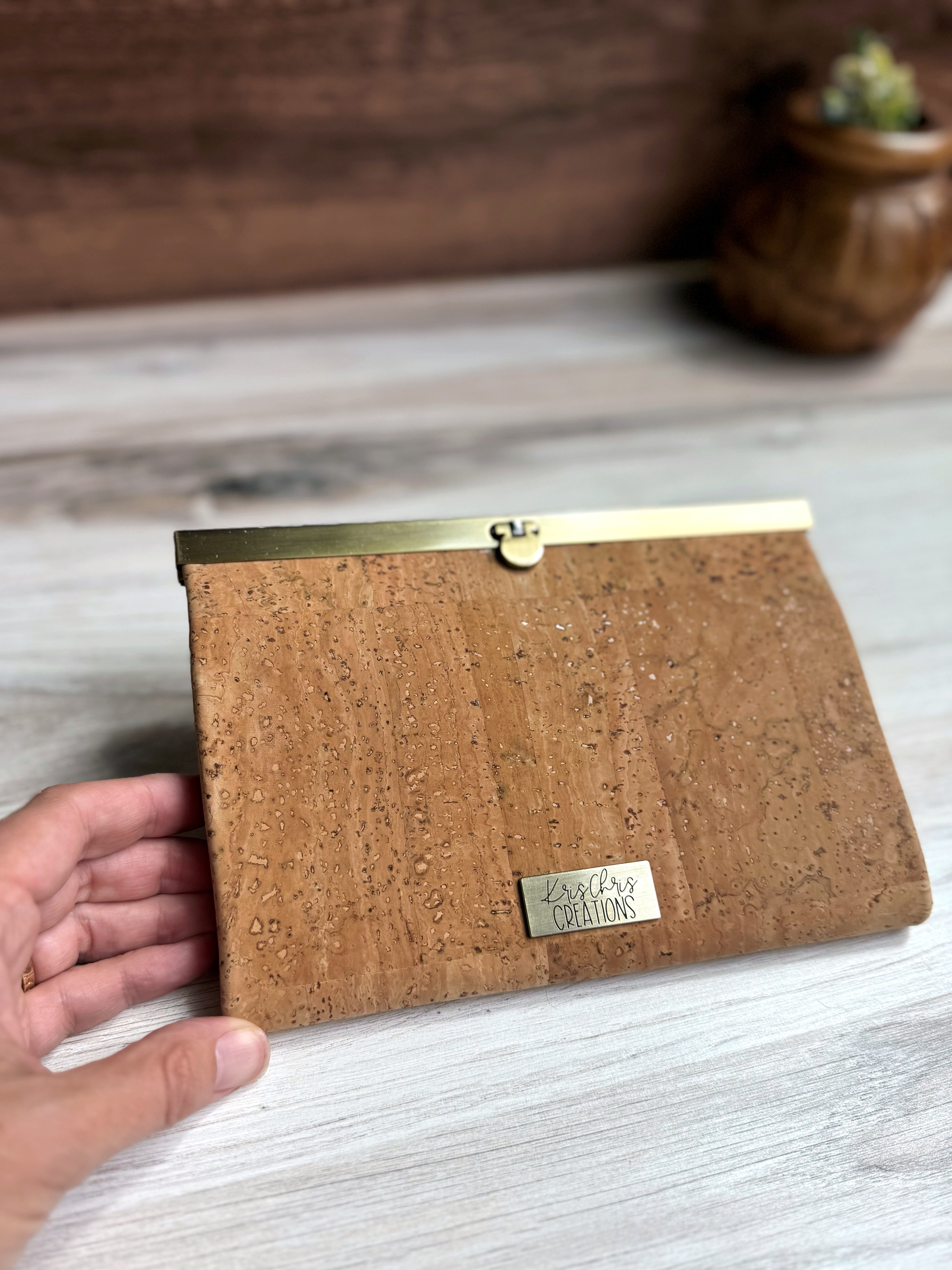 Light tan cork accordion wallet closed with antique brass top closure and KrisChris brass label.