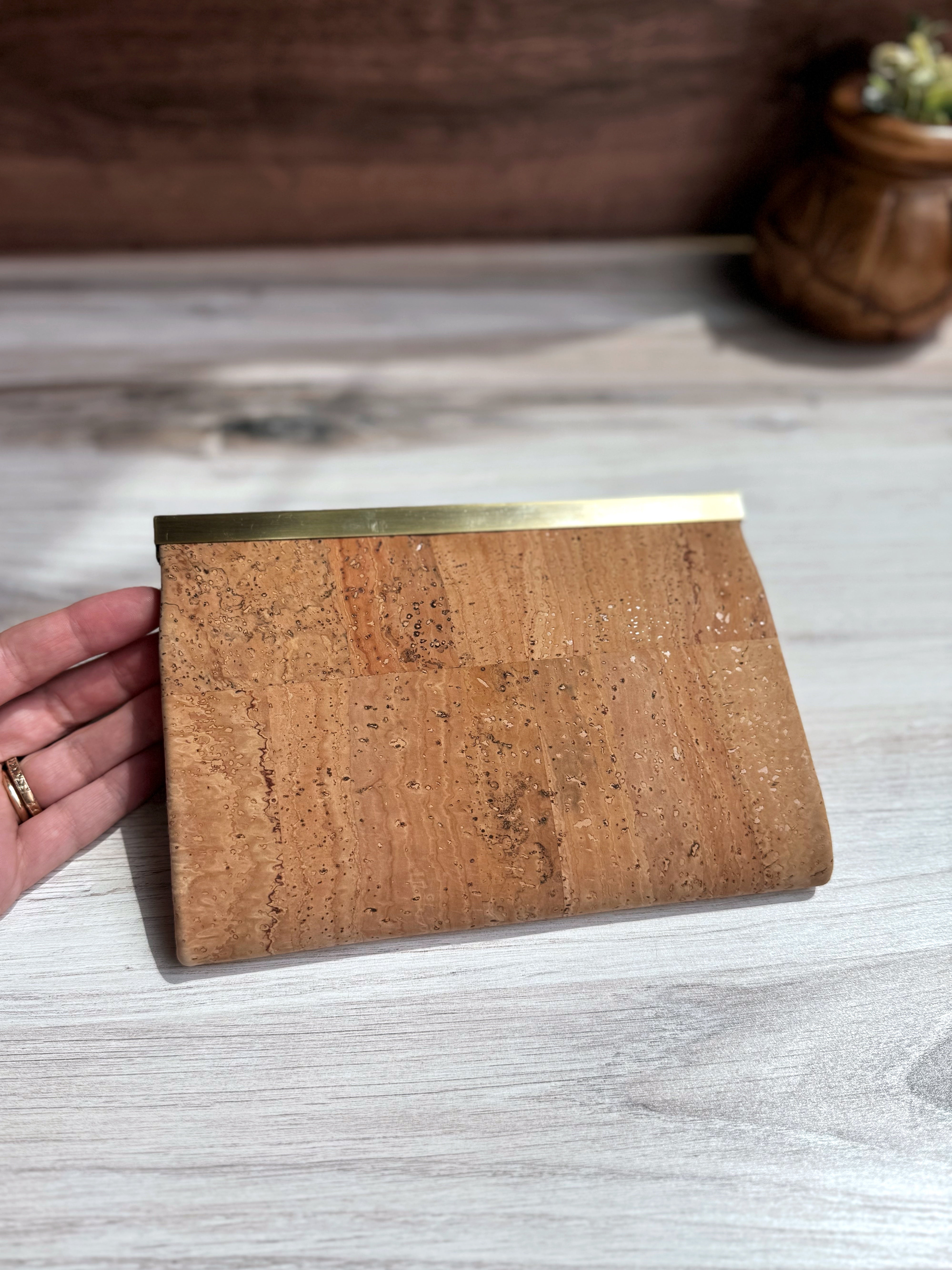 Light tan cork accordion wallet, back view with antique brass hardware strip along top edge