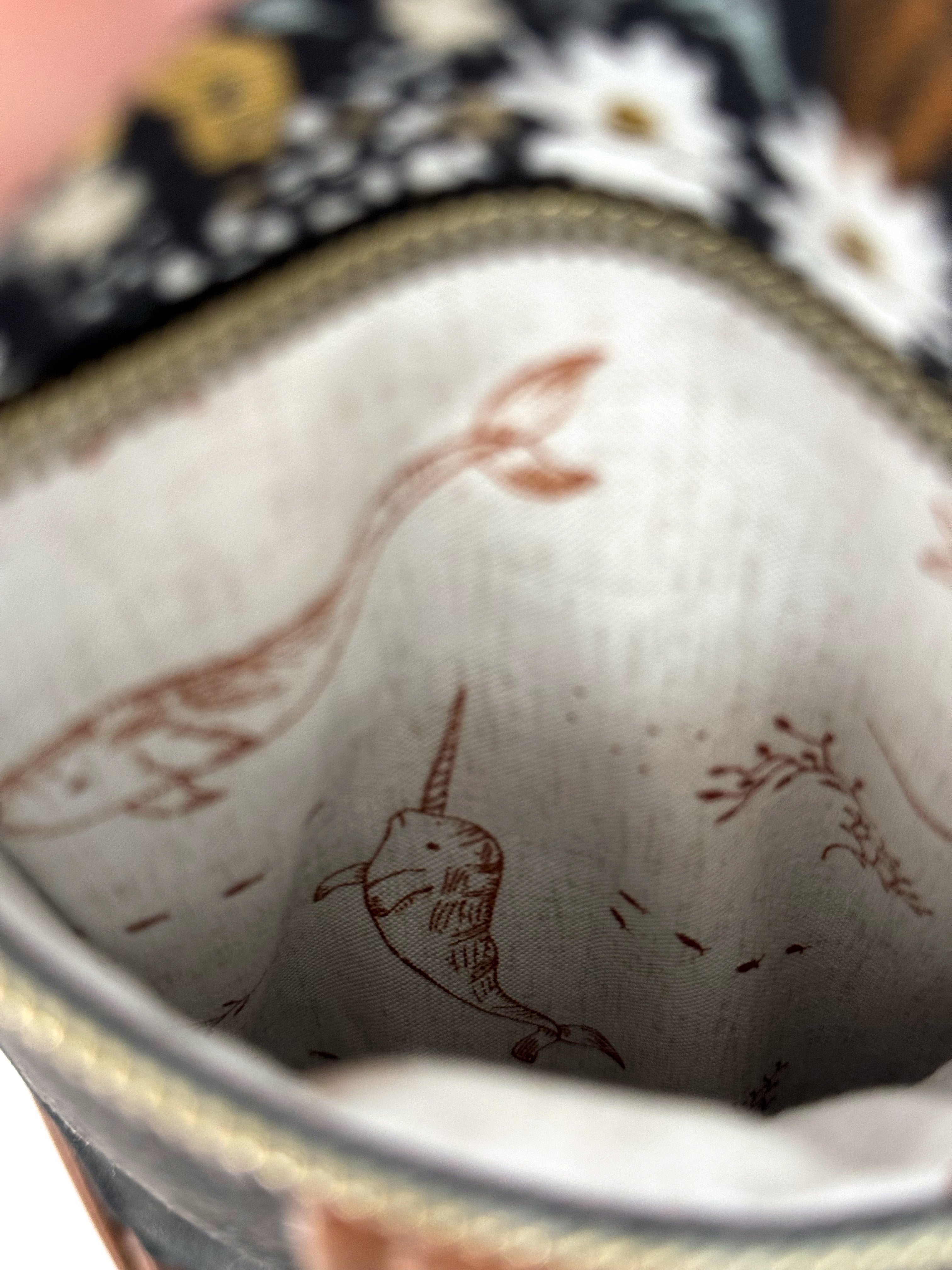 Interior of pocket of crossbody bag shows cute narwhals with light background