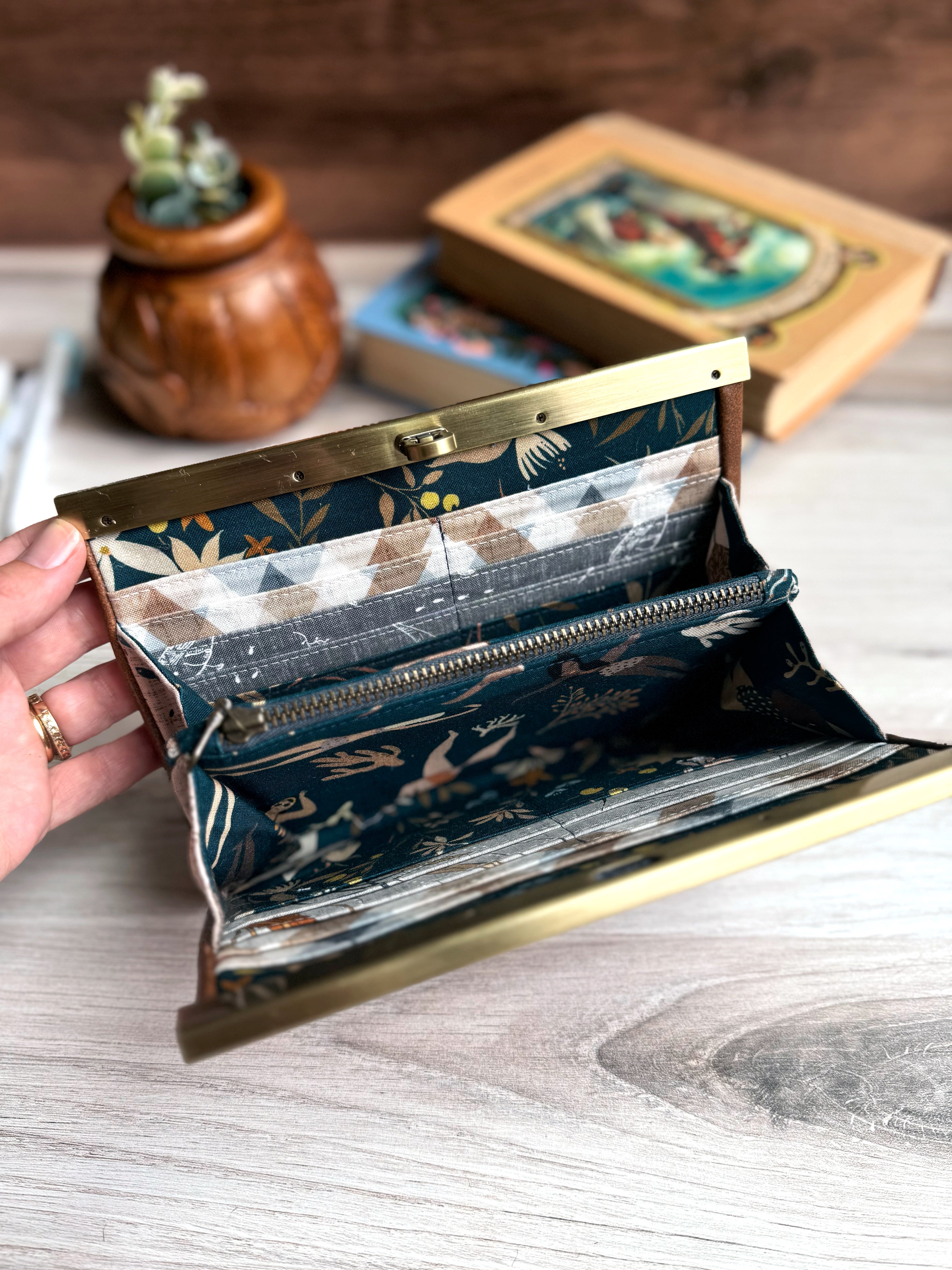 Open accordion wallet shows blue-green fabrics and many credit card slots and interior zipper pocket.