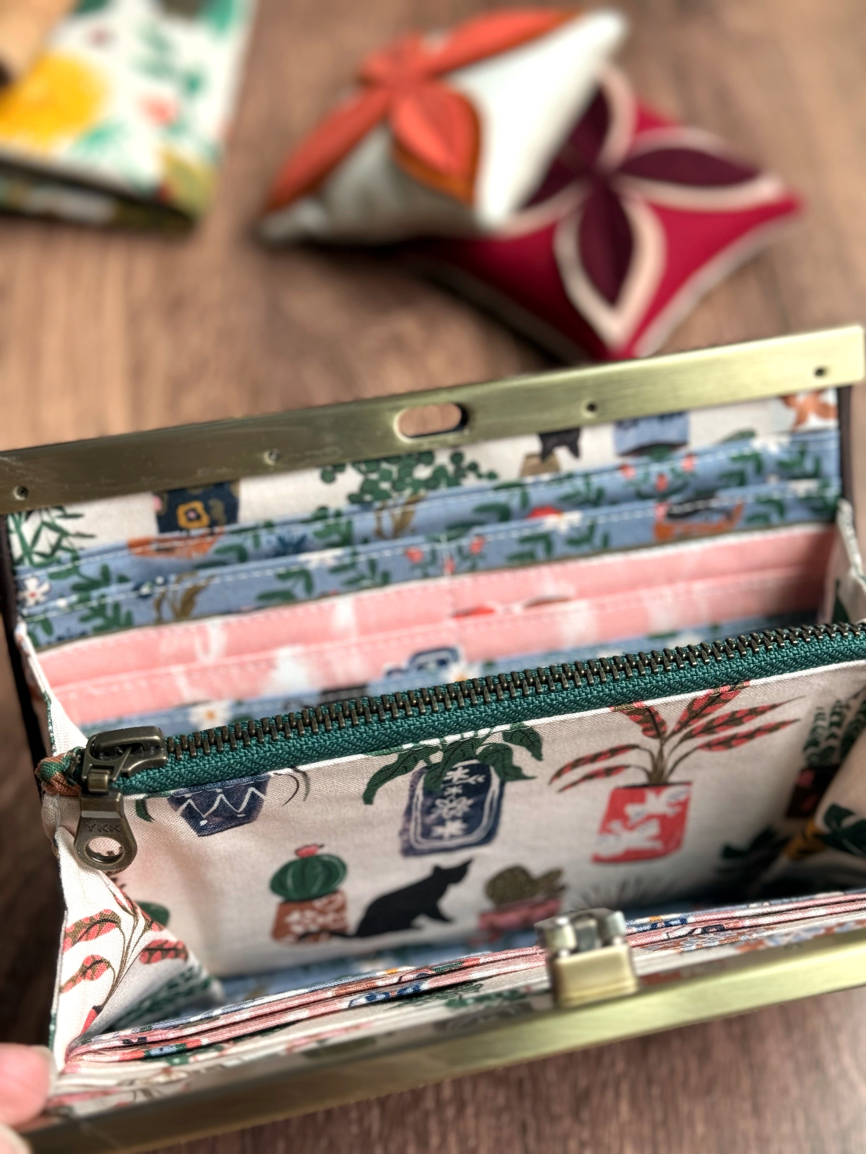 Accordion wallet with green zipper, many card slots, and adorable pink and blue fabric with house plants and black cats.