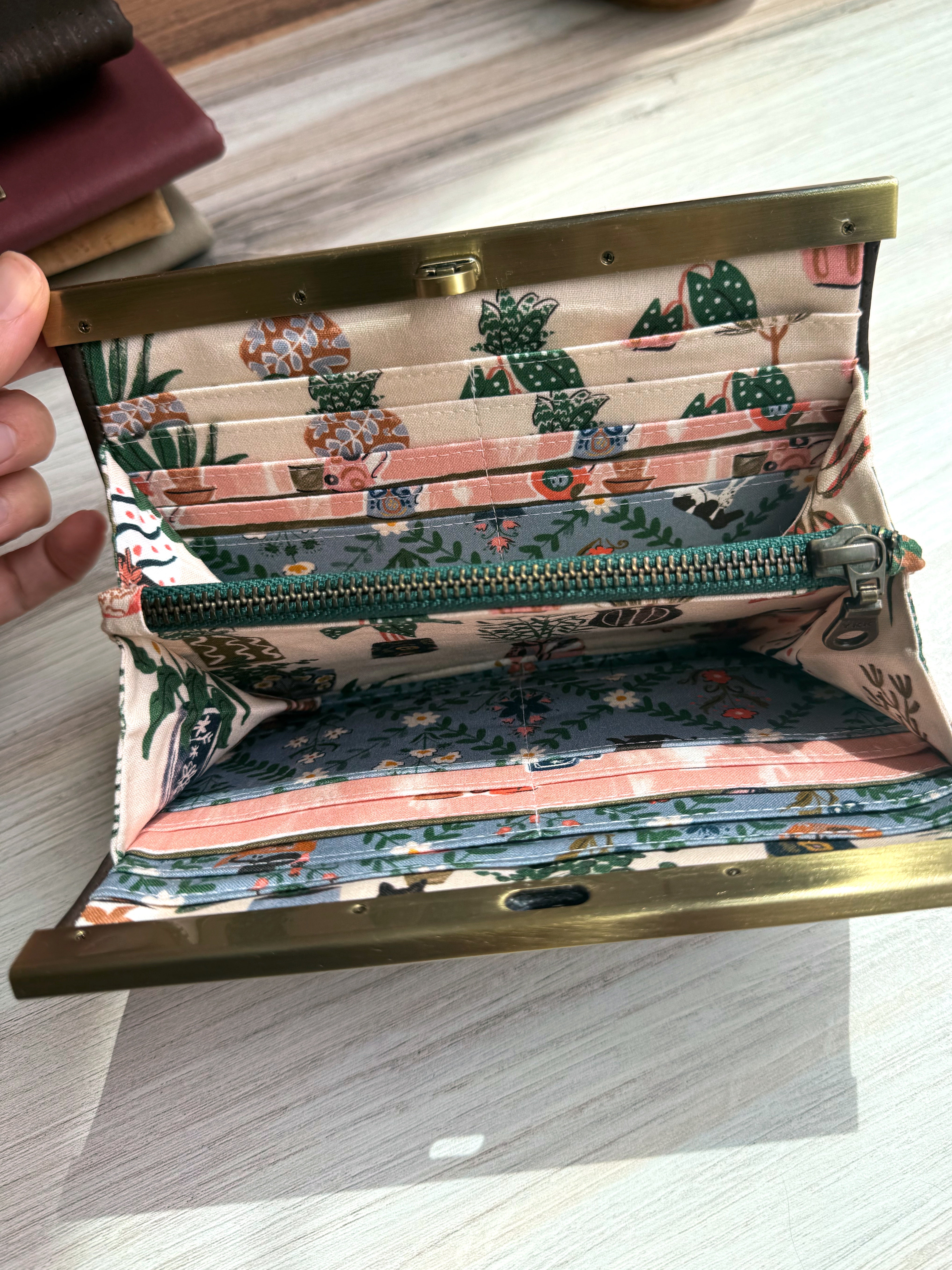 Accordion wallet with green zipper, many card slots, and adorable pink and blue fabric with house plants and black cats.