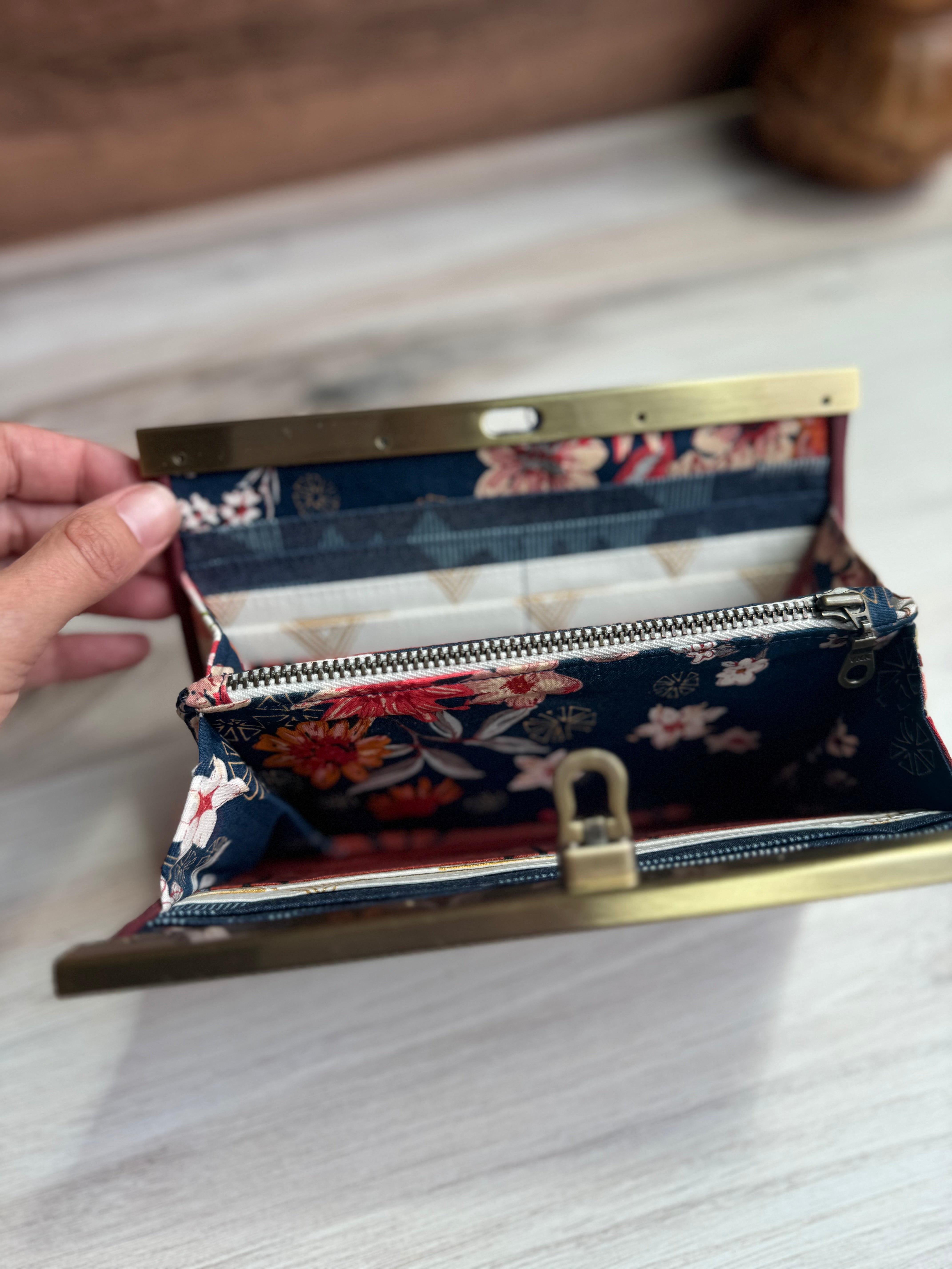 Open accordion wallet shows beautiful floral designs with navy background, and card slots with white and blue geometric fabrcis.