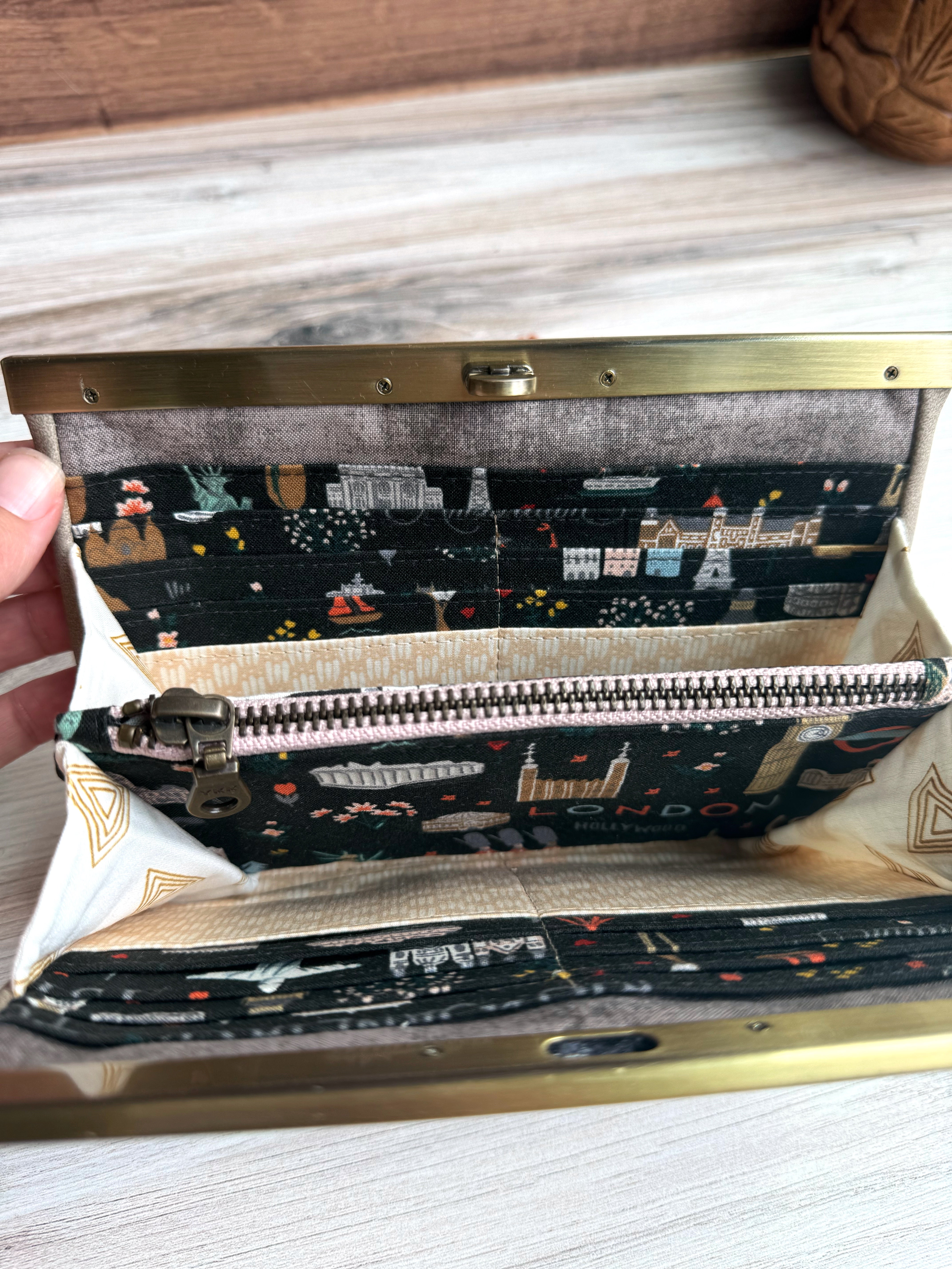 Gray/Tan accordion style wallet opened to show zipper pocket and fun illustrated Rifle Paper fabrics featuring iconic world images