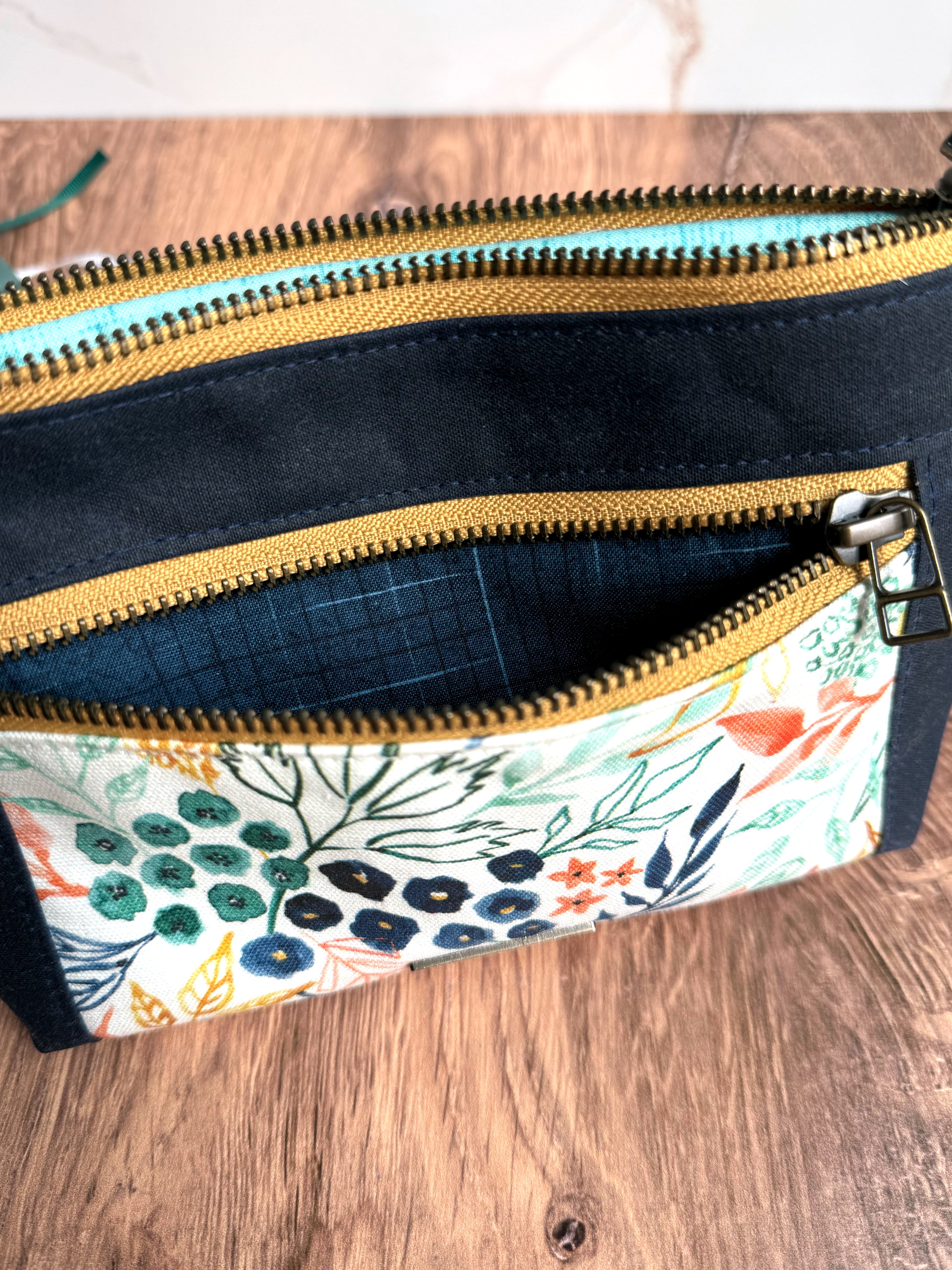 2 yellow zippers open on a navy pouch with striped navy lining fabric