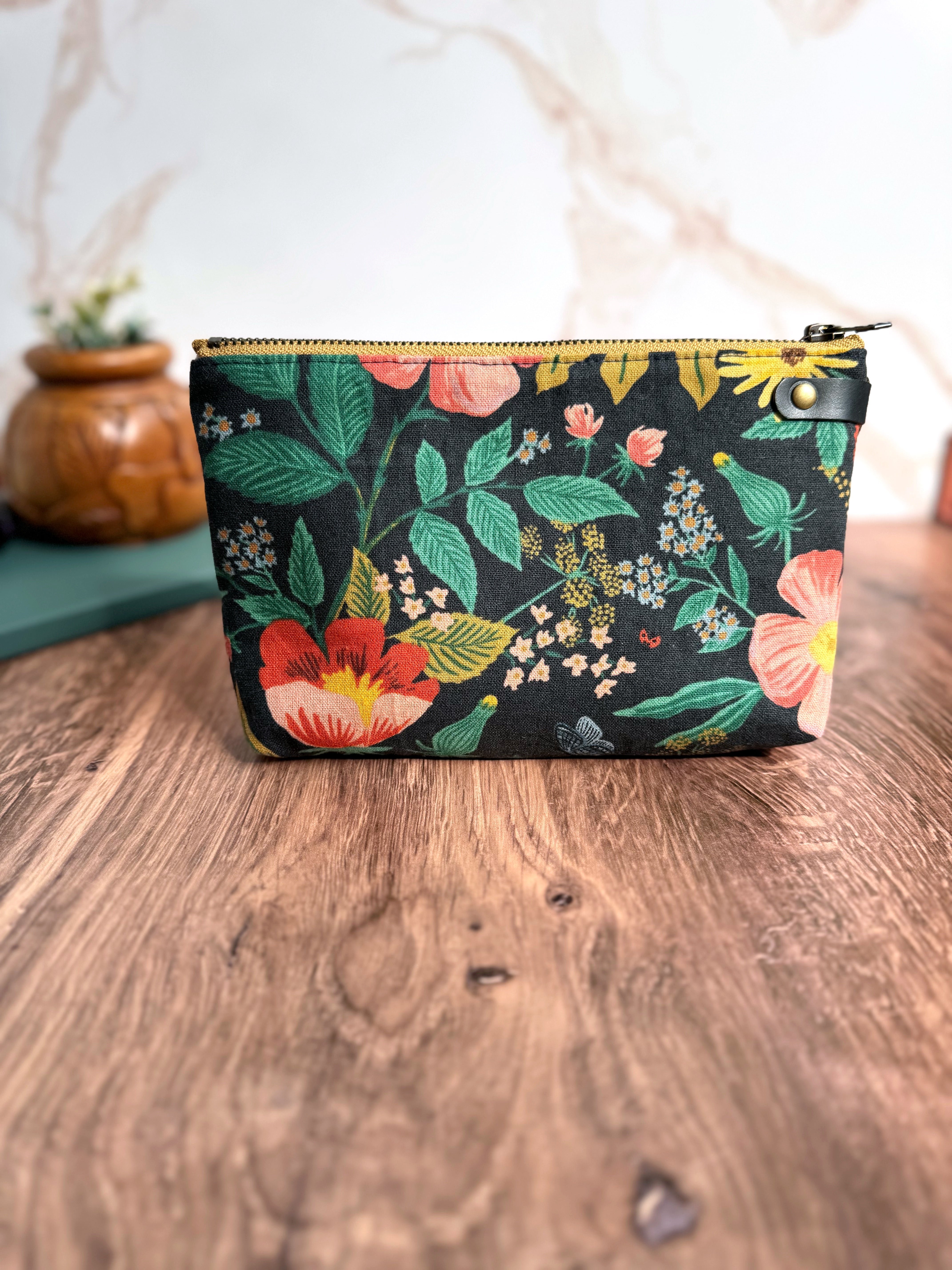 Floral pouch in Rifle Paper Co. canvas illustrated fabric with wooden flooring and marble backdrop.