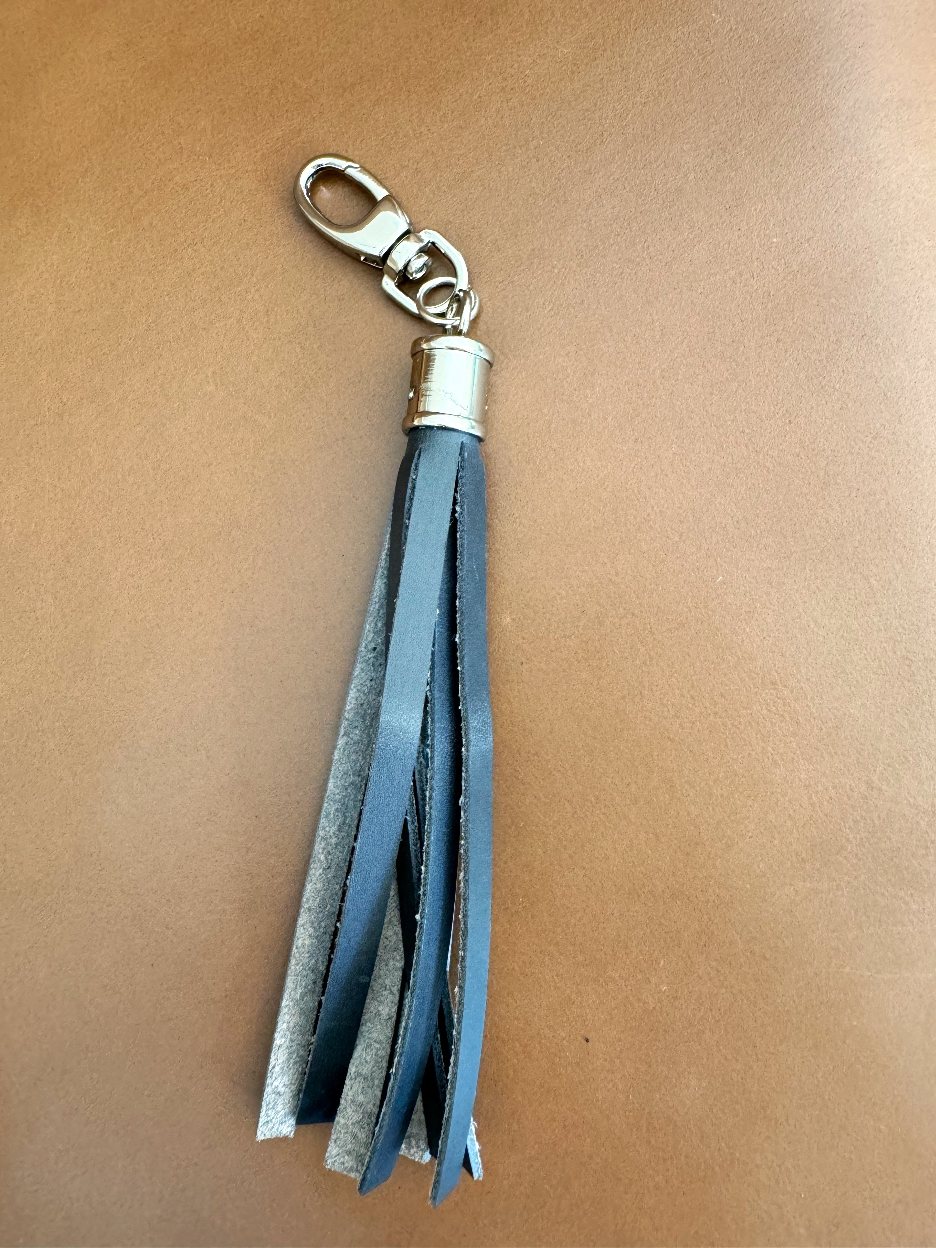 Tassel with navy fringe and cylindrical nickel hardware. Lobster clasp easily attaches to bags and accessories.