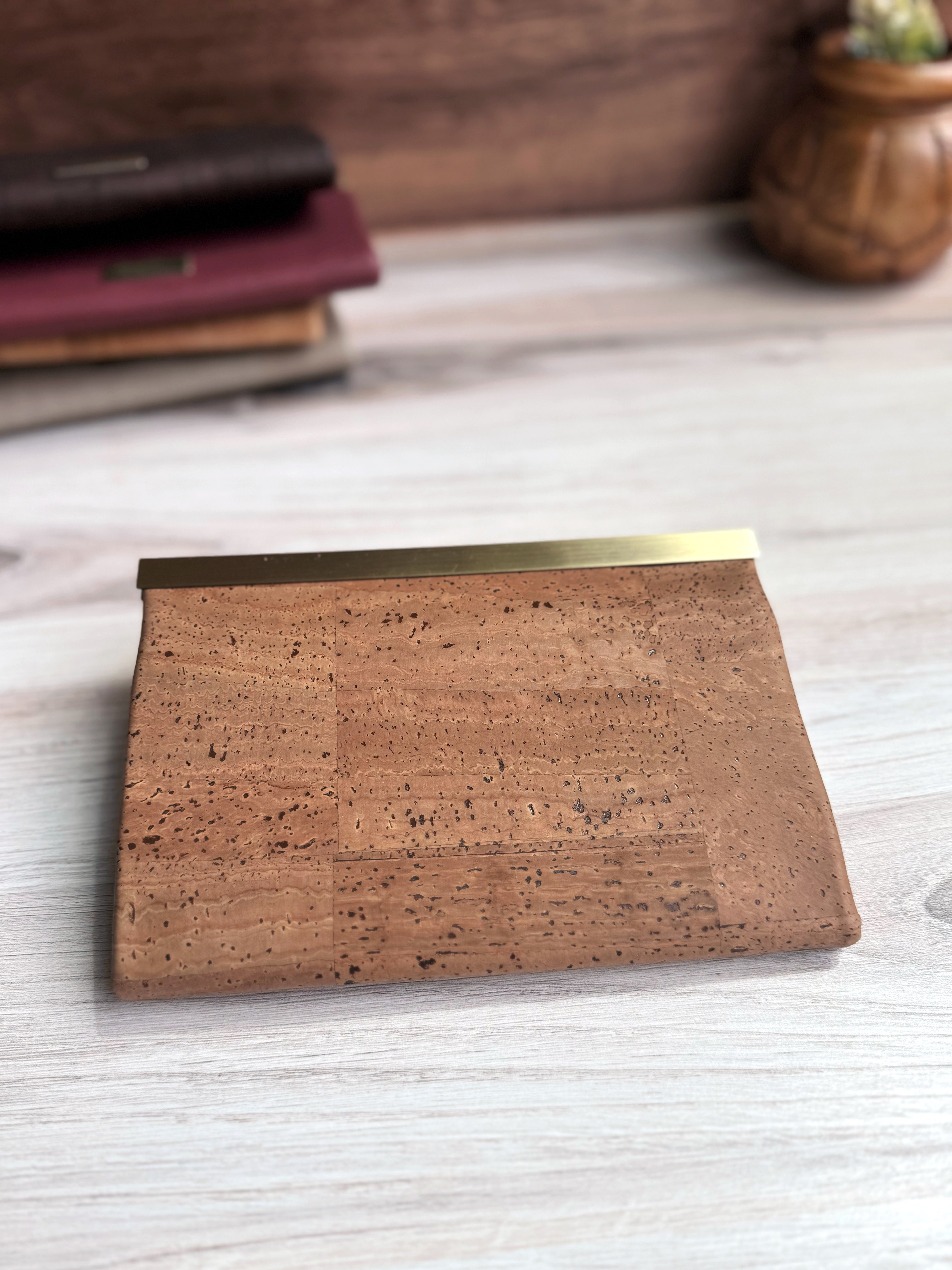 Rear view of tan cork accordion wallet with antique brass closure strip along top edge