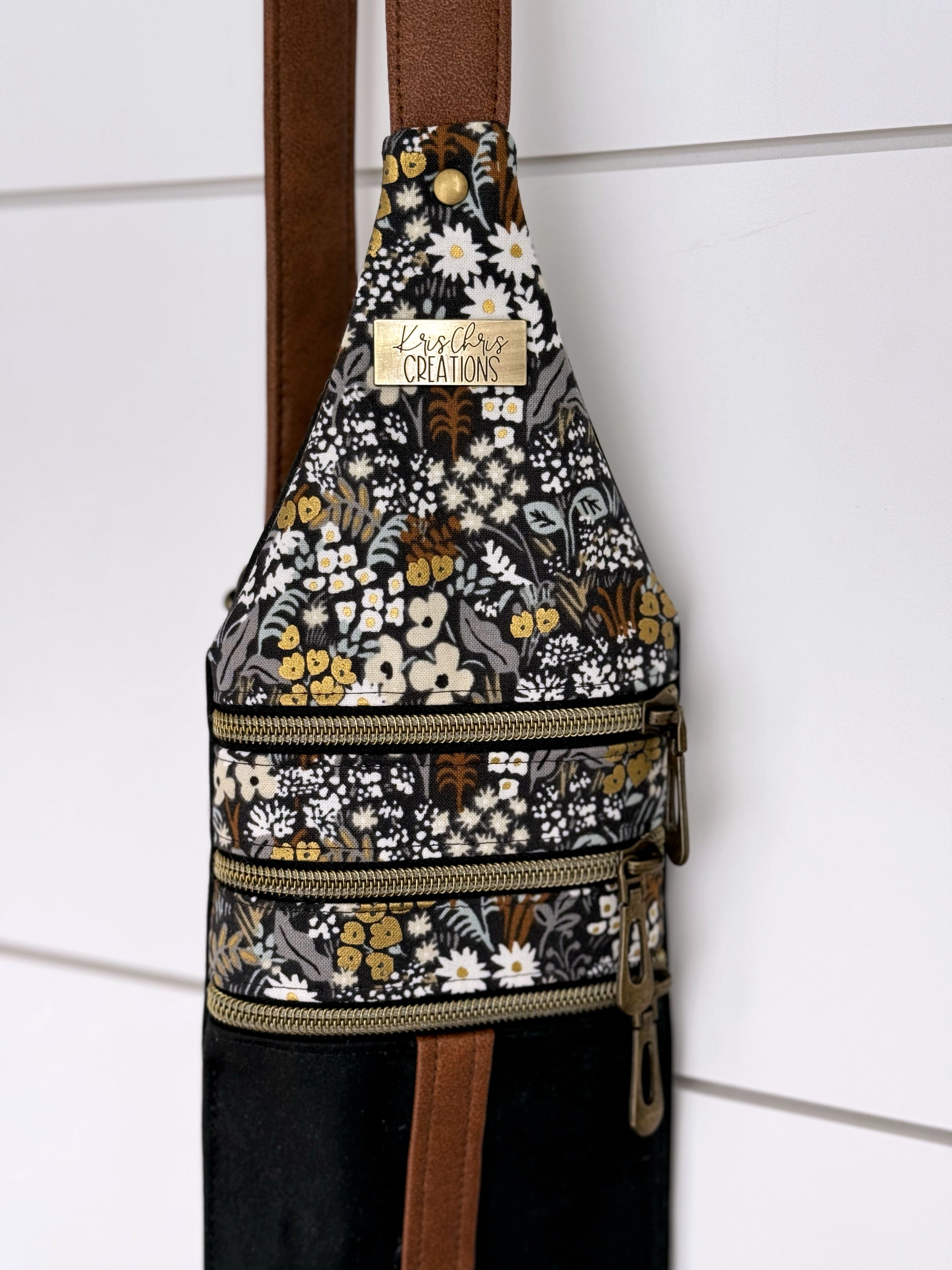 Top of Brown and Black floral crossbody bag with 3 zippers closed and antique brass KrisChris label.