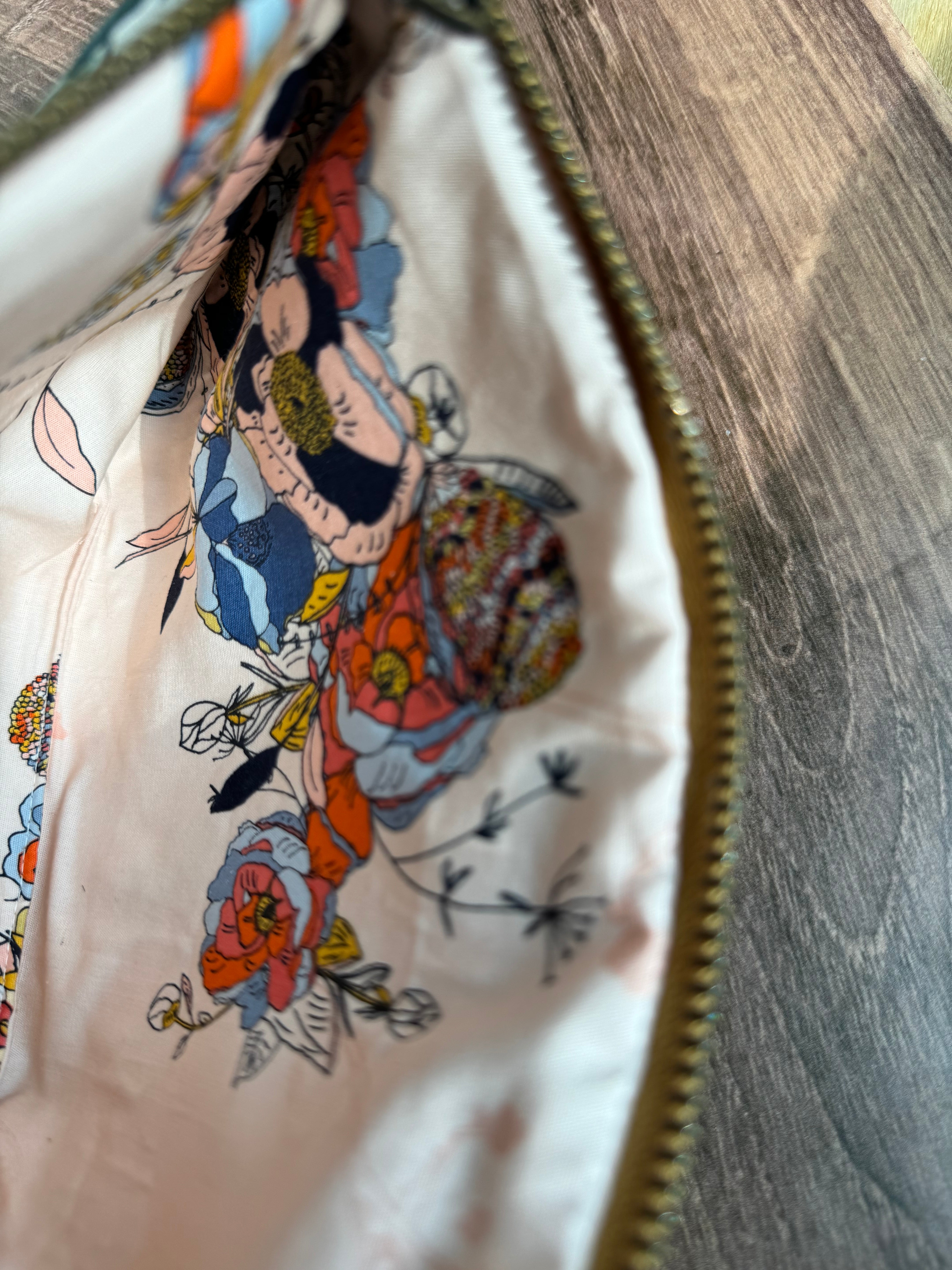 Larger zipper pocket is open to show light pink, coral, and blue illustrated fabrics inside.