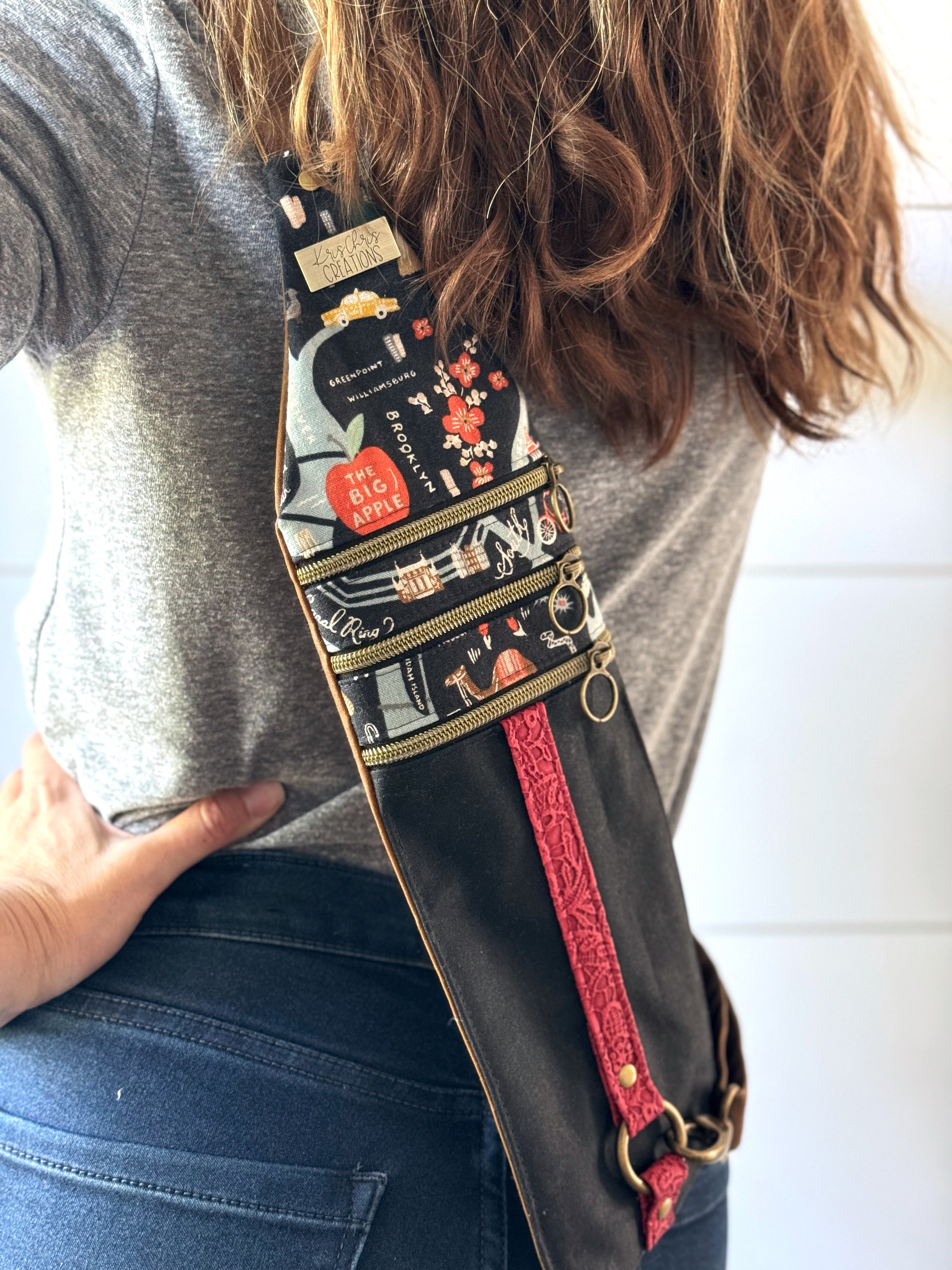 Crossbody bag worn on back with adjustable straps and 3 zippers.