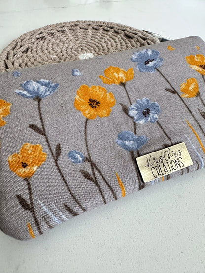 Closeup of a gray wallet with yellow and blue flowersand brass label. 
