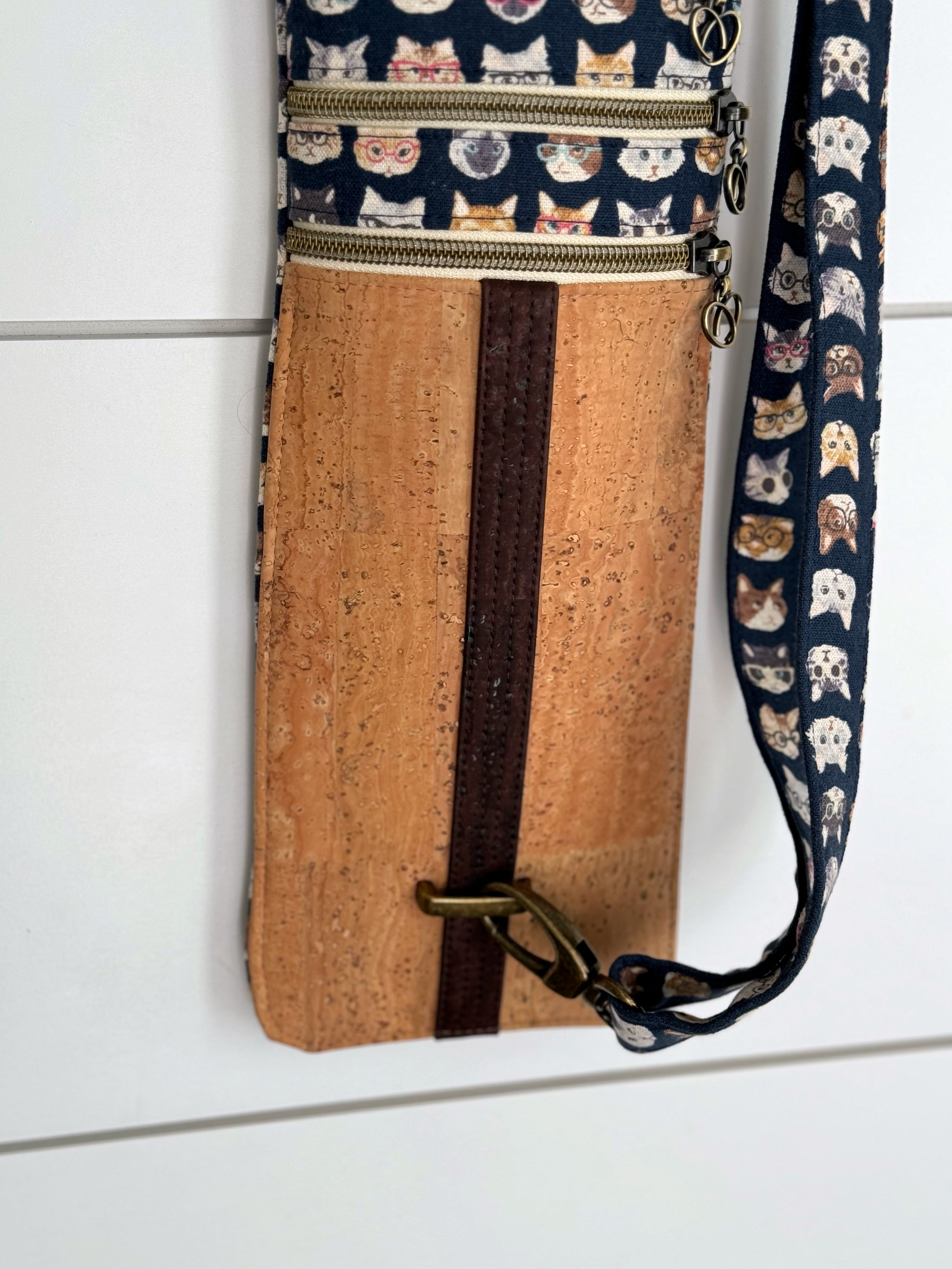 A strip of chocolate brown cork fabric detail over the light cork fabric shows brass hardware that allow the bag to be adjusted and customized.