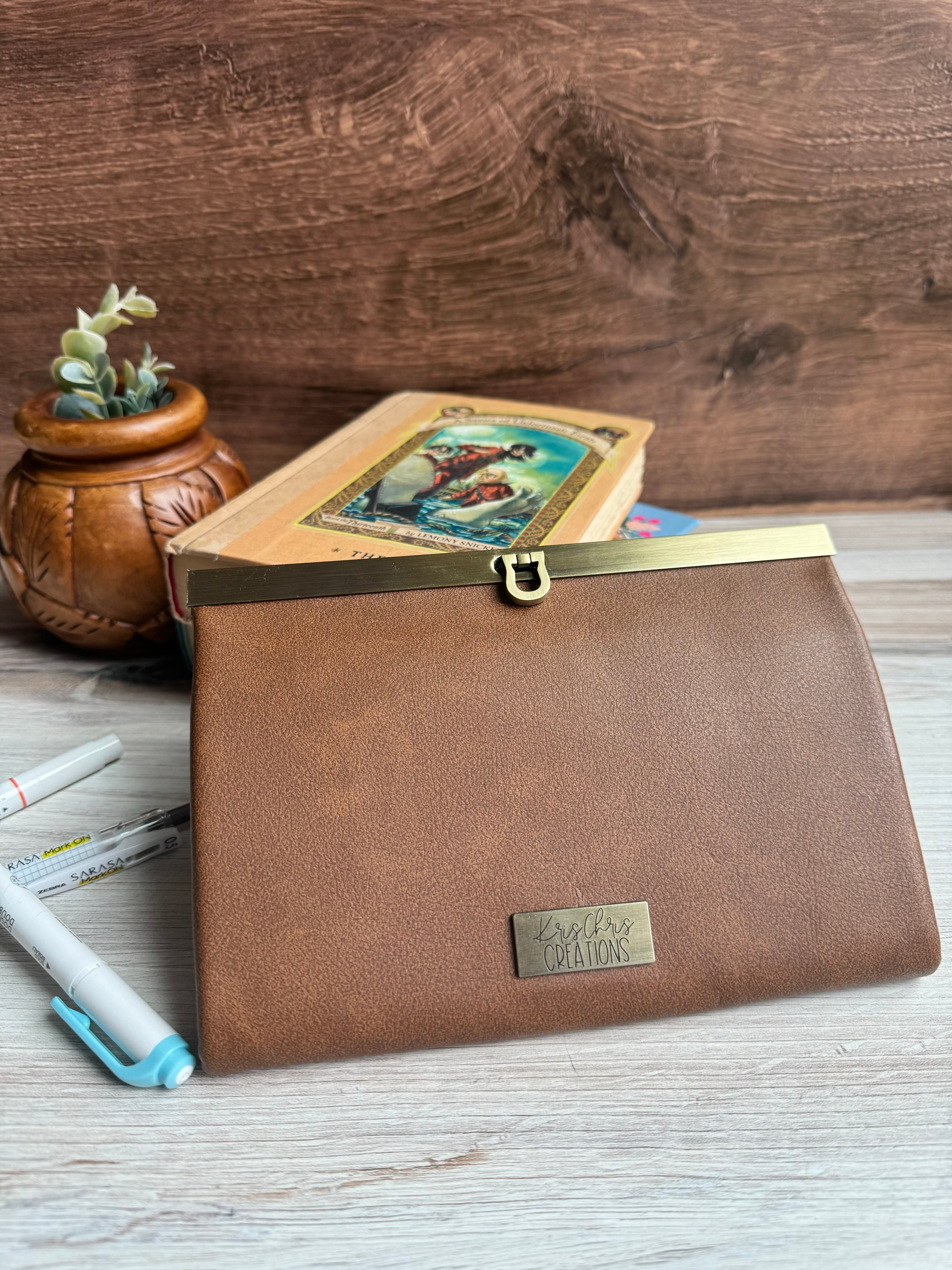 Tan Vinyl (vegan leather) accordion wallet, closed with antique brass hardware along top edge. Folds in compact rectangle.