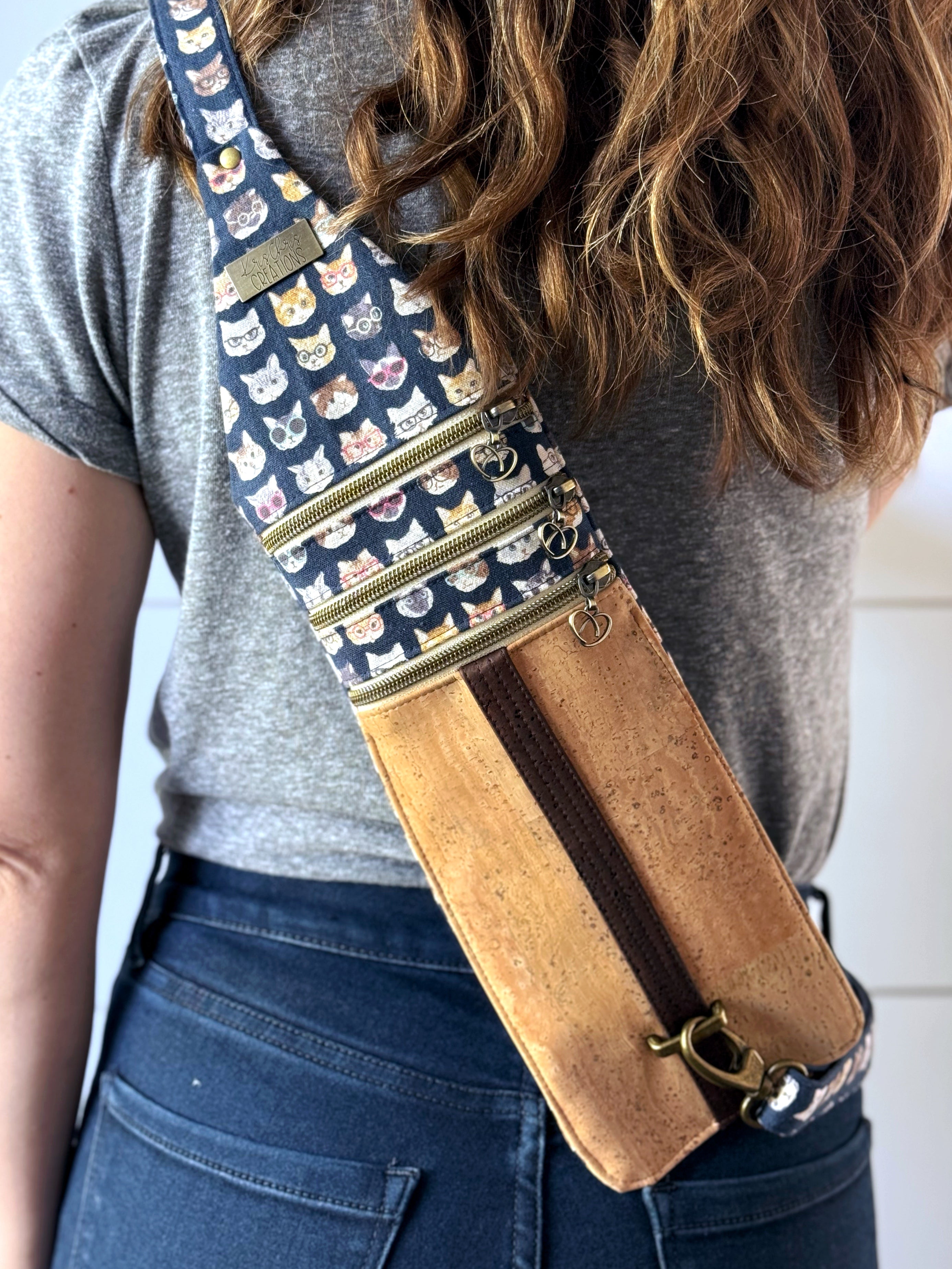 Sling bag is worn on the back, Navy canvas fabric with different cat breeds wearing glasses, and light cork fabric is at the bottom 