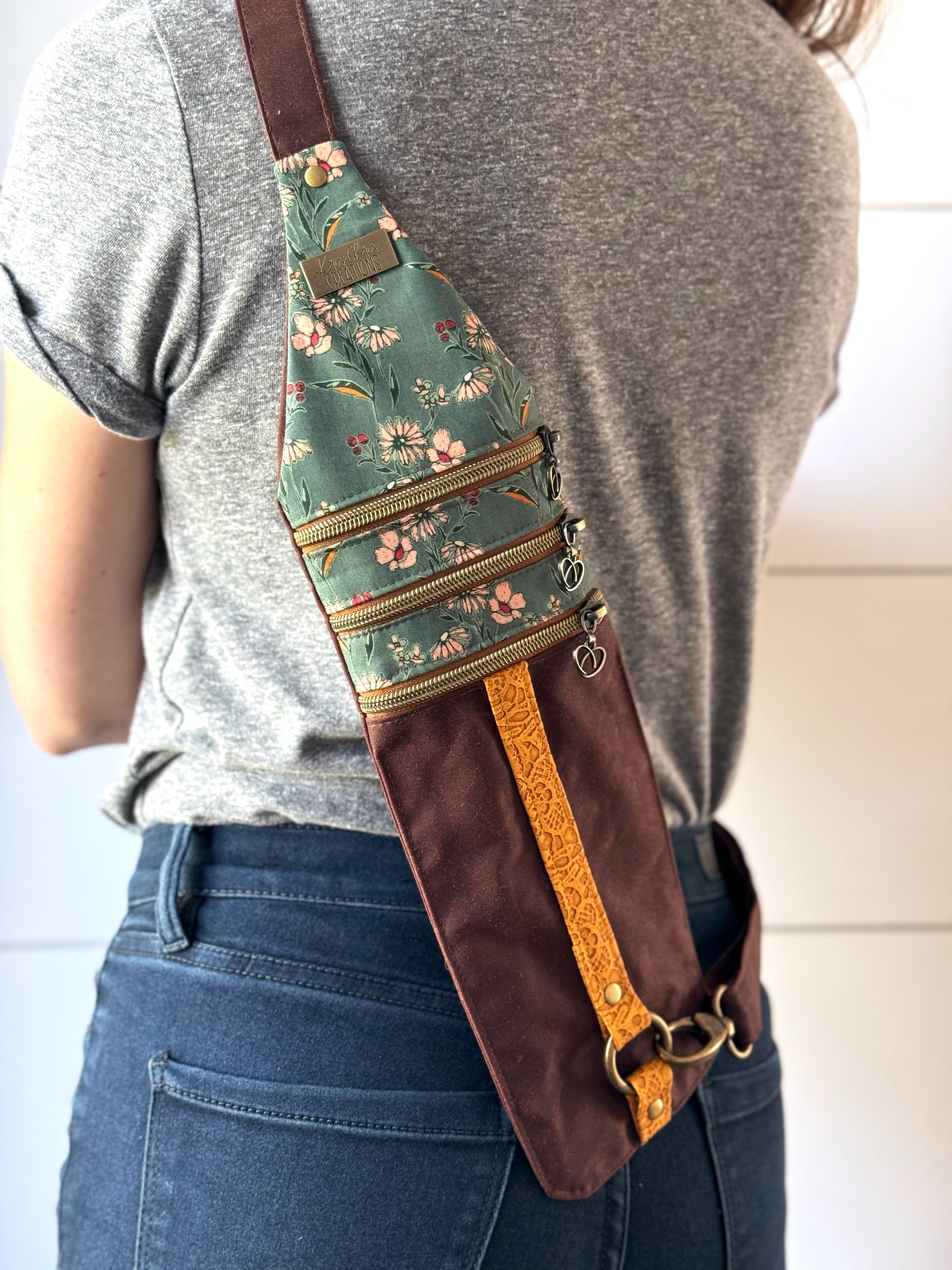 Red brown crossbody bag worn on the back with teal floral fabric on top and a yellow lace vinyl stripe