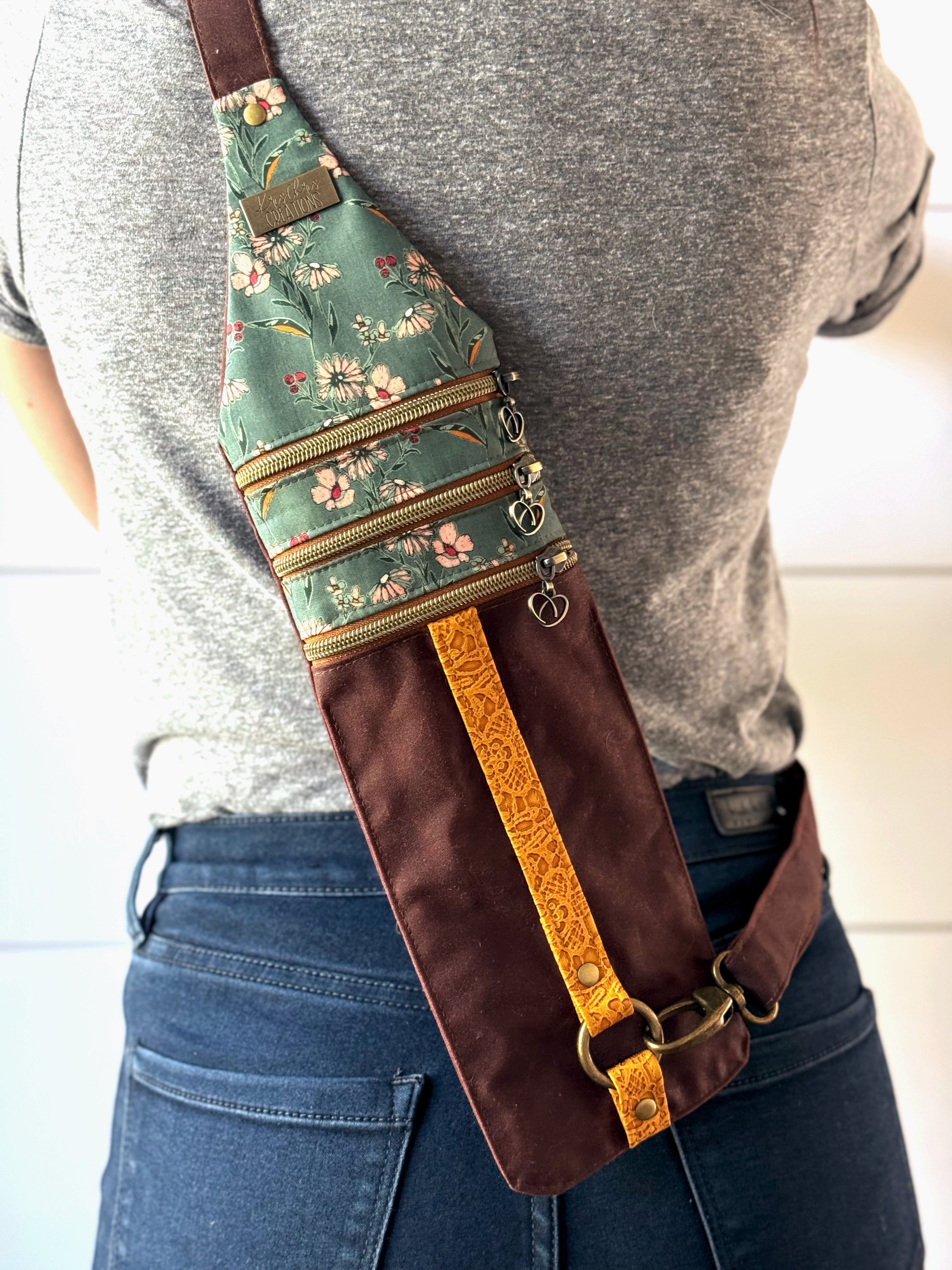 Red brown crossbody bag worn on the back with teal floral fabric on top and a yellow lace vinyl stripe