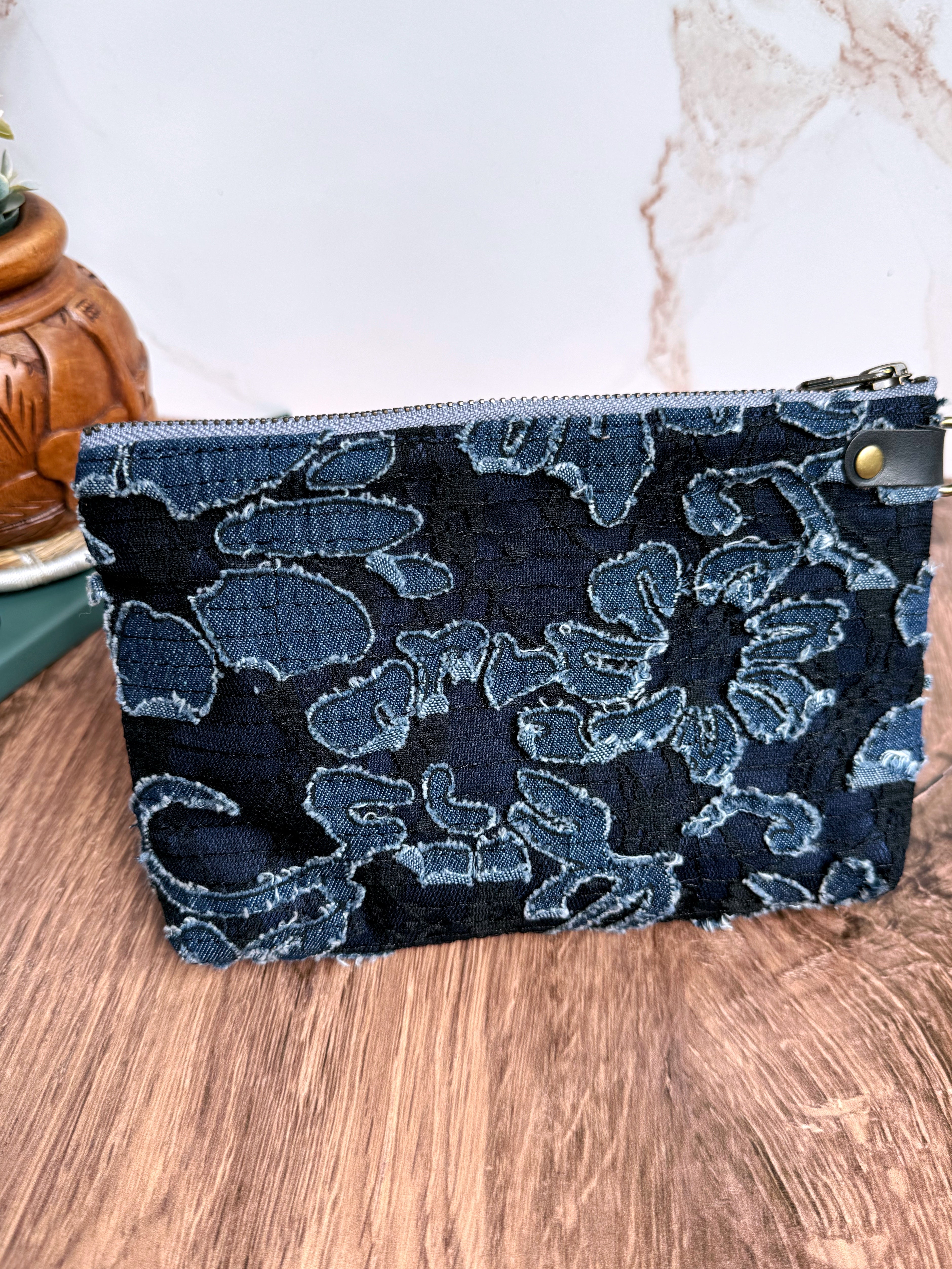 Back panel of navy pouch shows textured denim flowers that have been appliqued. 