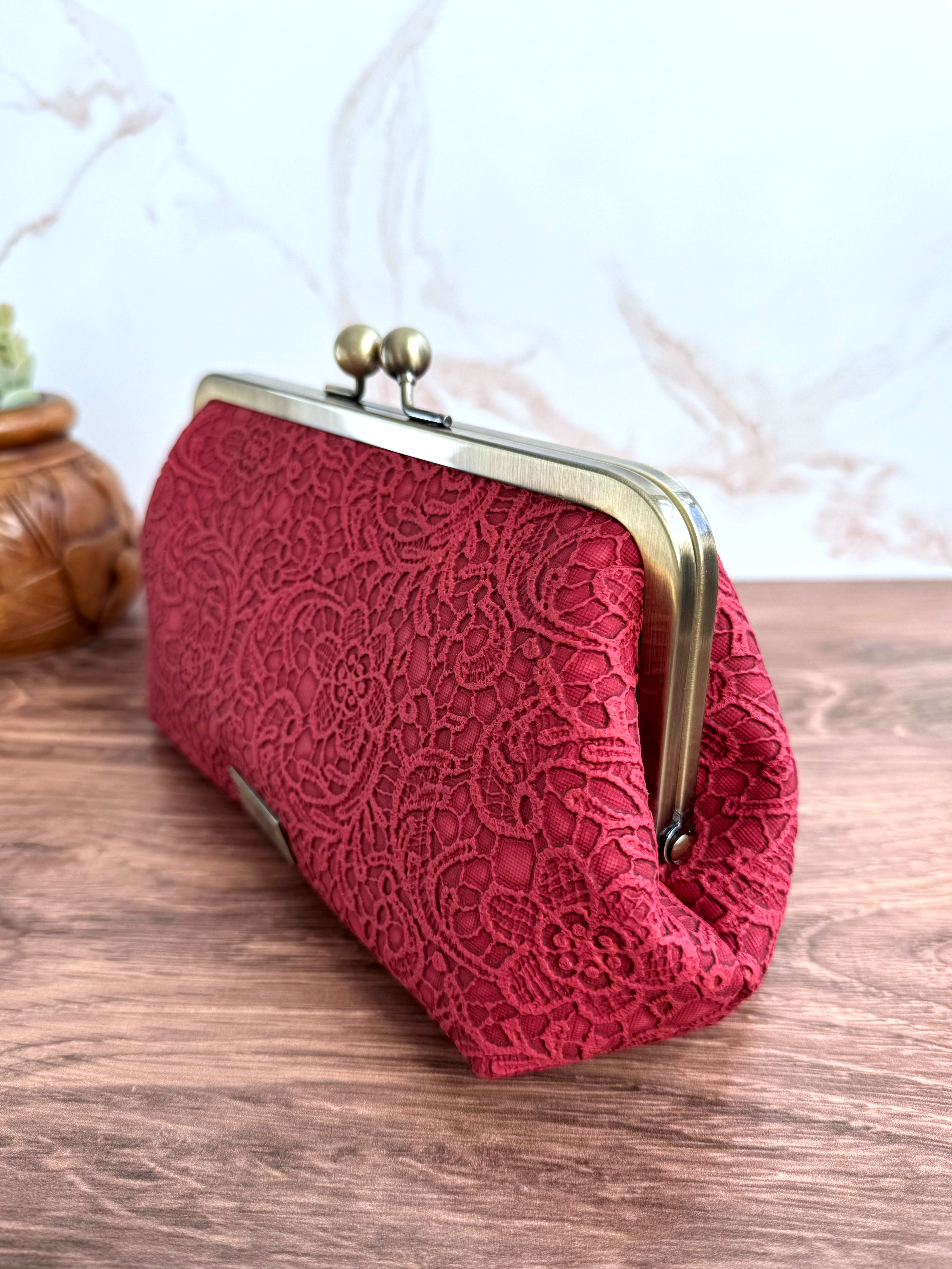 Closed red lace vinyl clutch at an angle