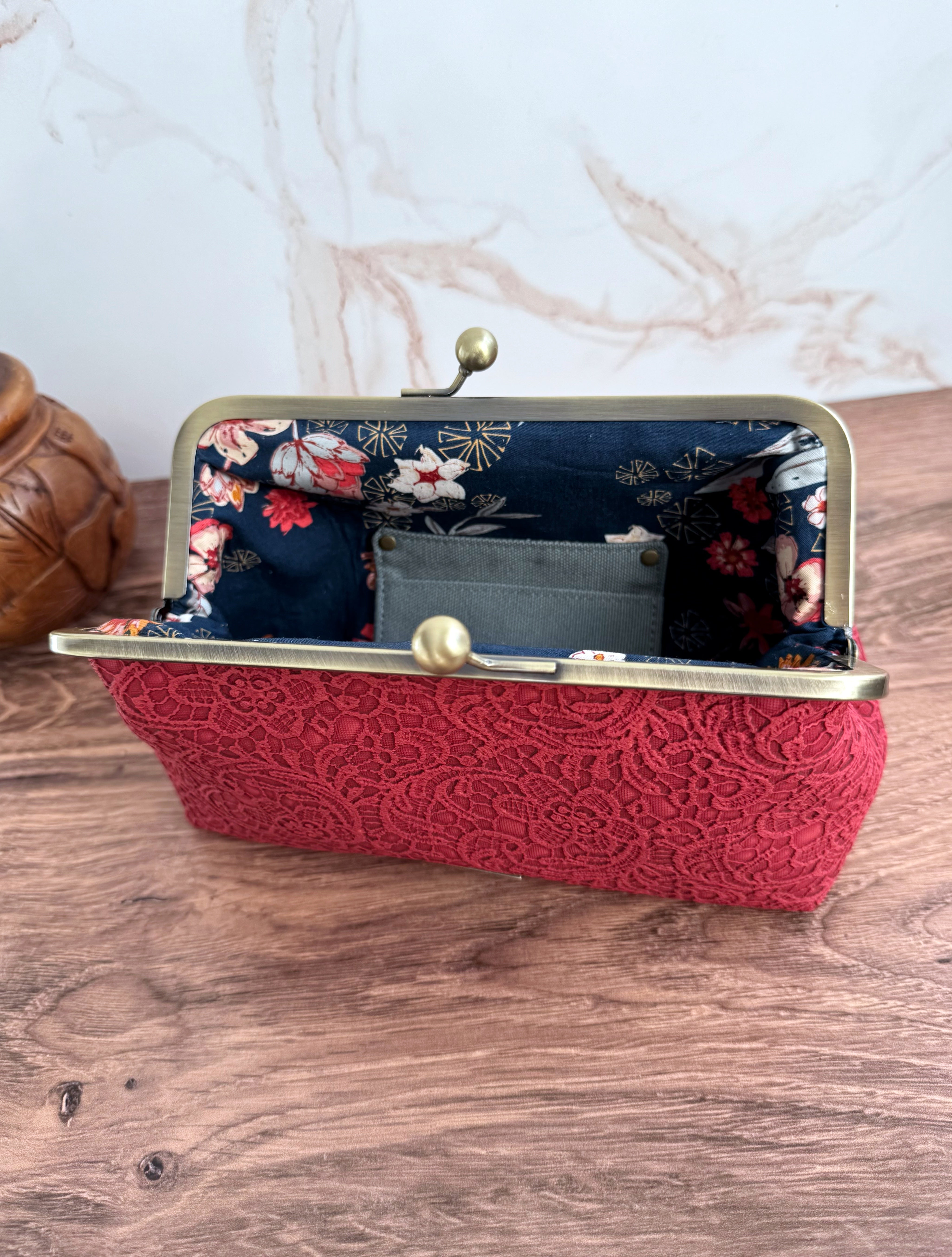 Opened clutch bag with brass frame and navy floral interior