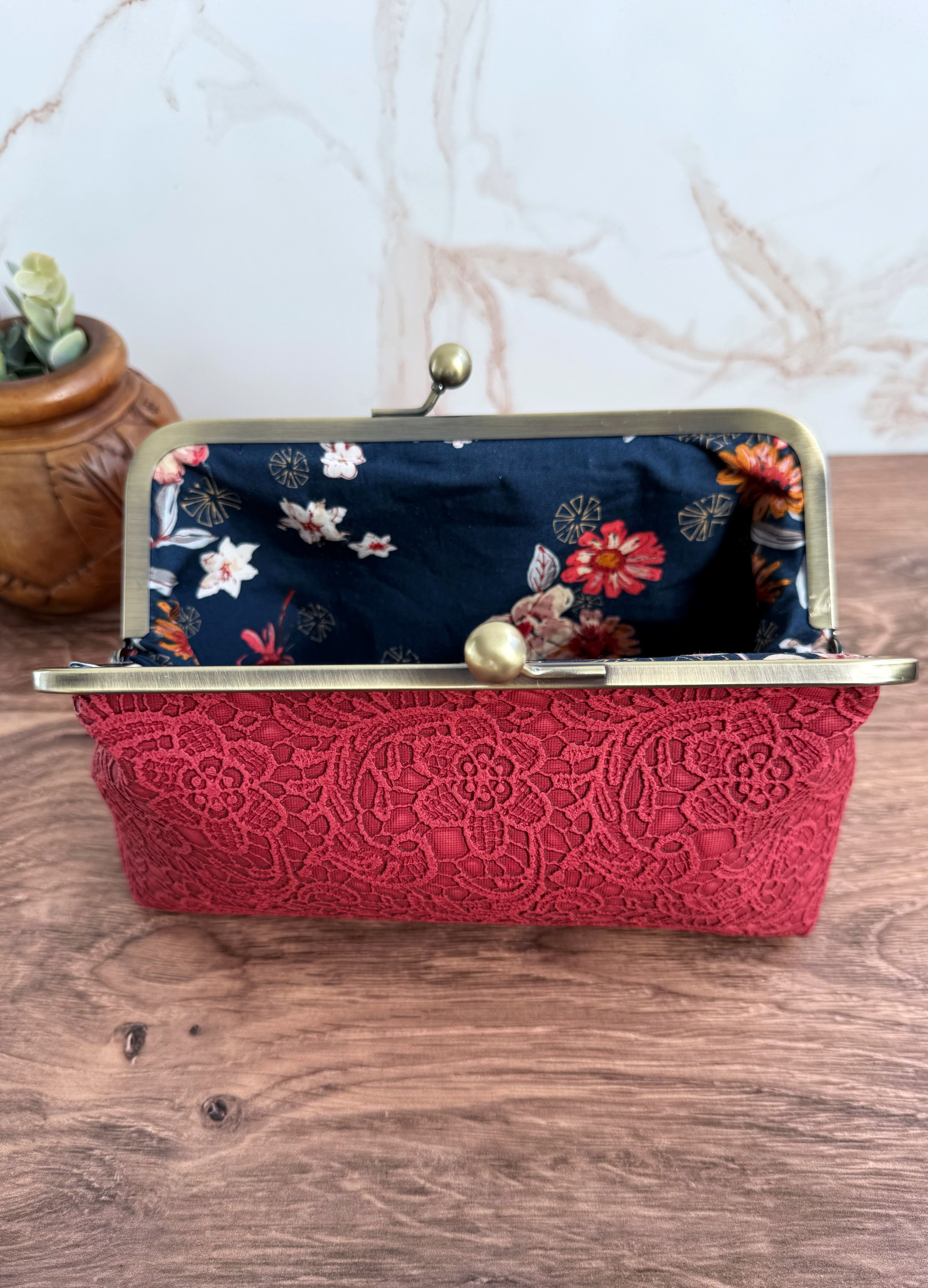 Opened red lace vinyl clutch bag with navy floral interior