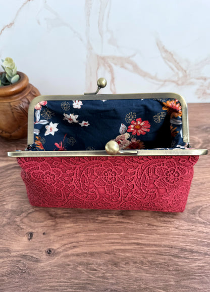 Opened red lace vinyl clutch bag with navy floral interior