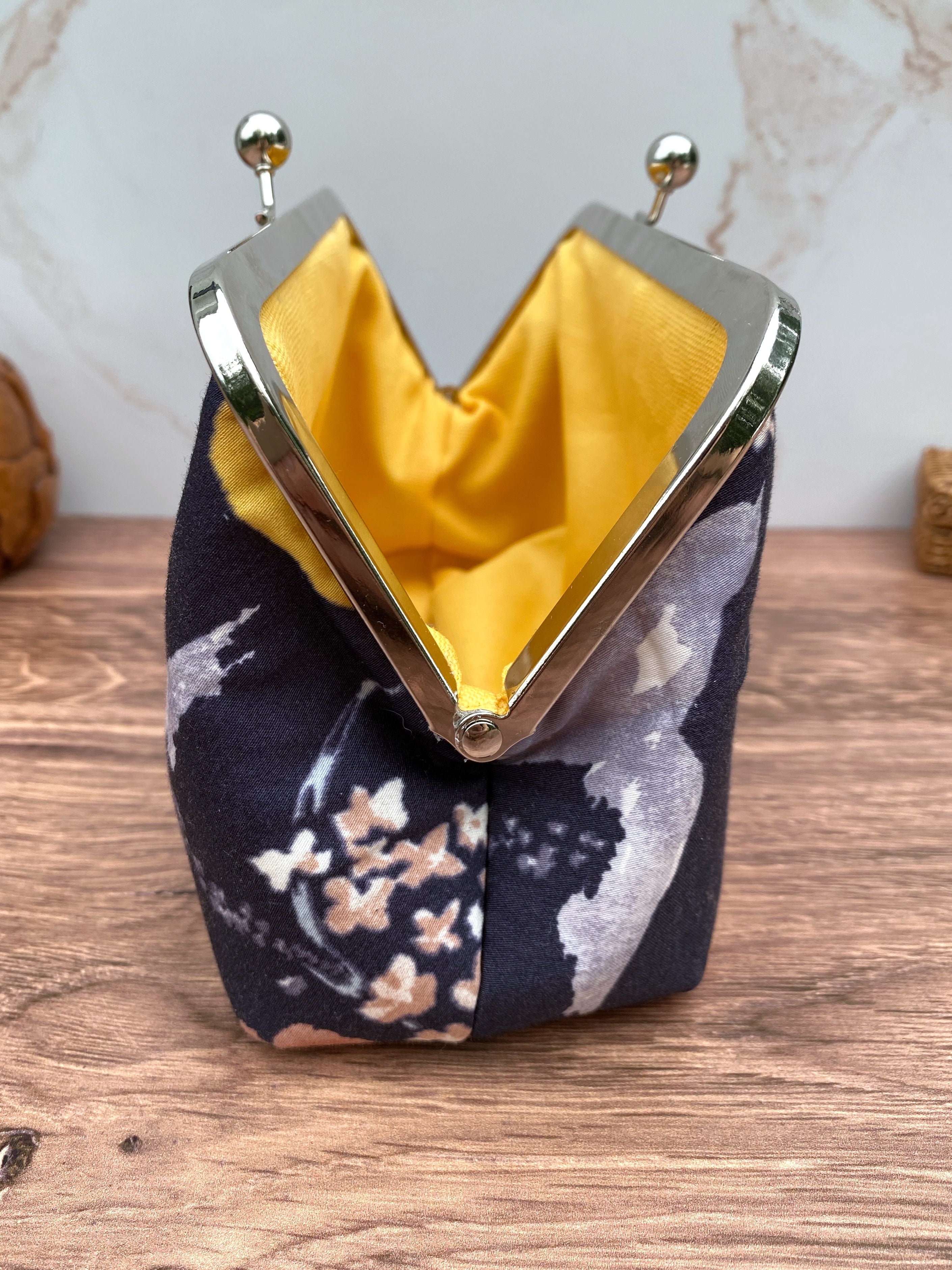 Side view of Navy floral twist lock clutch opened to show yellow canvas lining