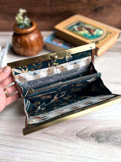 Open accordion wallet shows blue-green fabrics and many credit card slots and interior zipper pocket.
