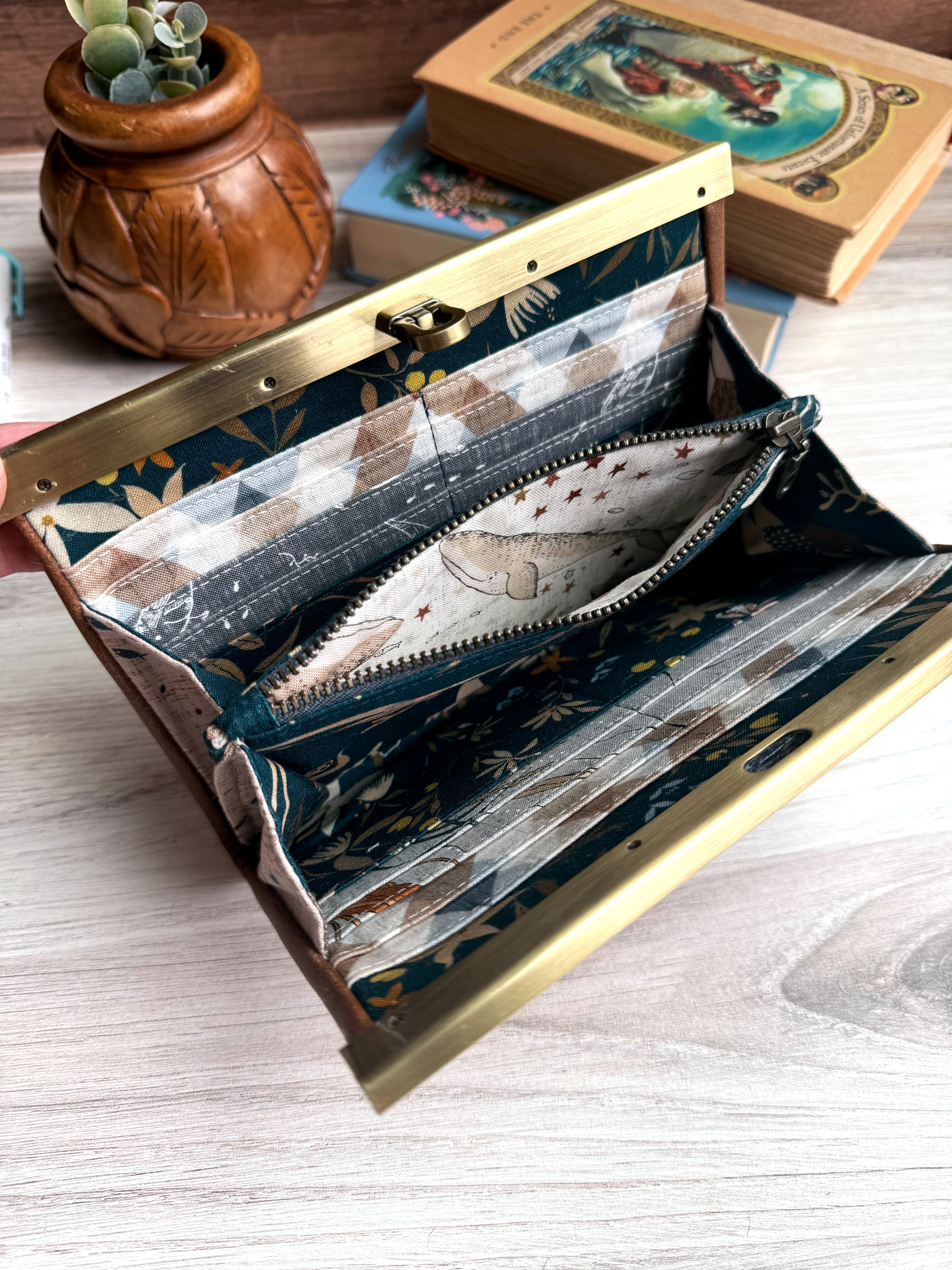 Open accordion wallet with fish and whale themed fabrics on interior.  Middle zipper pocket opens up with a whale fabric inside.  Antique brass closure is on the top. 