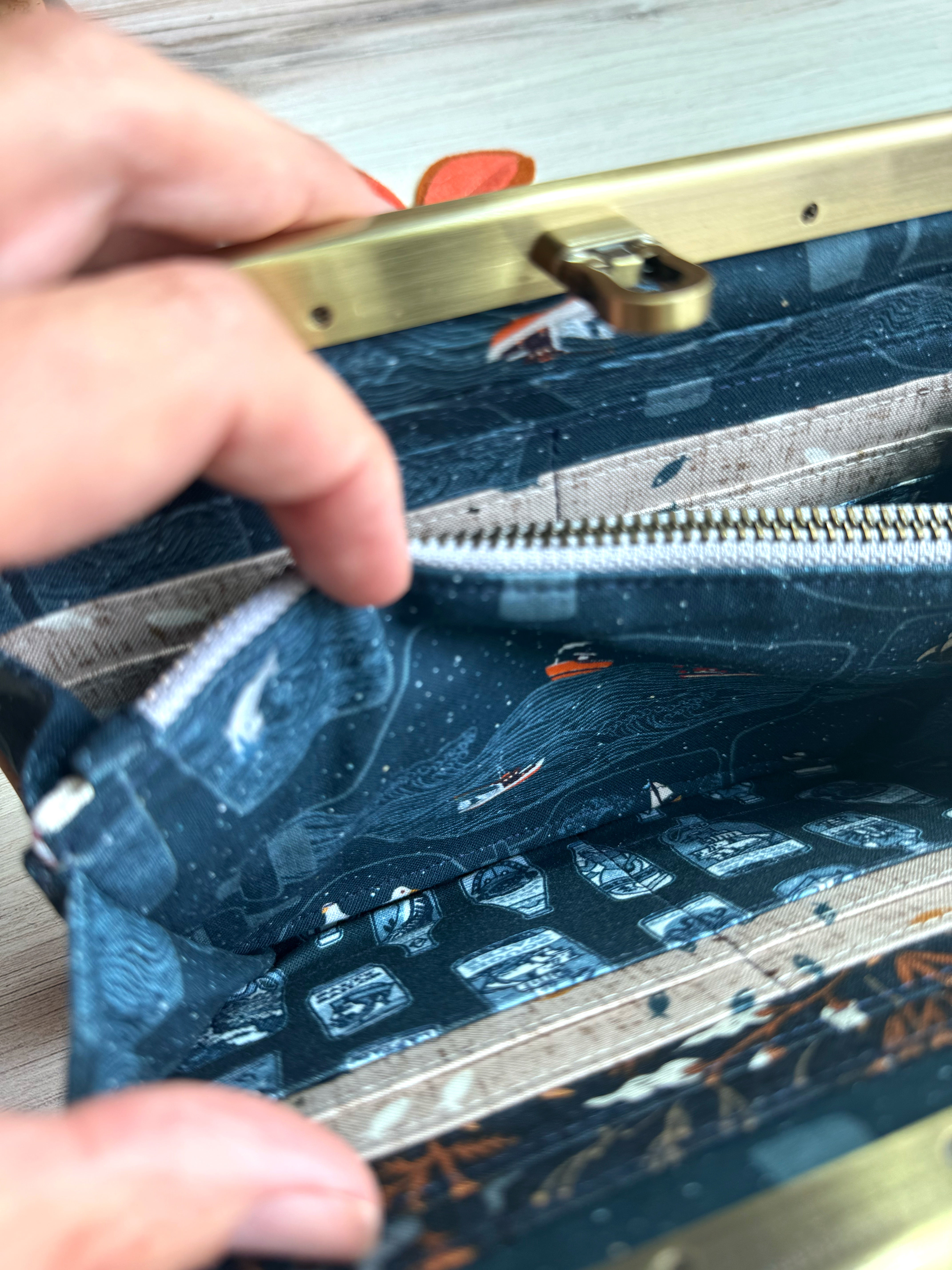 Open accordion wallet shows fabric  illustrations with ocean, boat, fish and pirate bottles. 