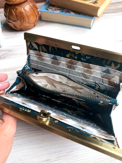 Open accordion wallet shows whale fabric on a cream background on interior zipper pocket.  Many card slots as well. 