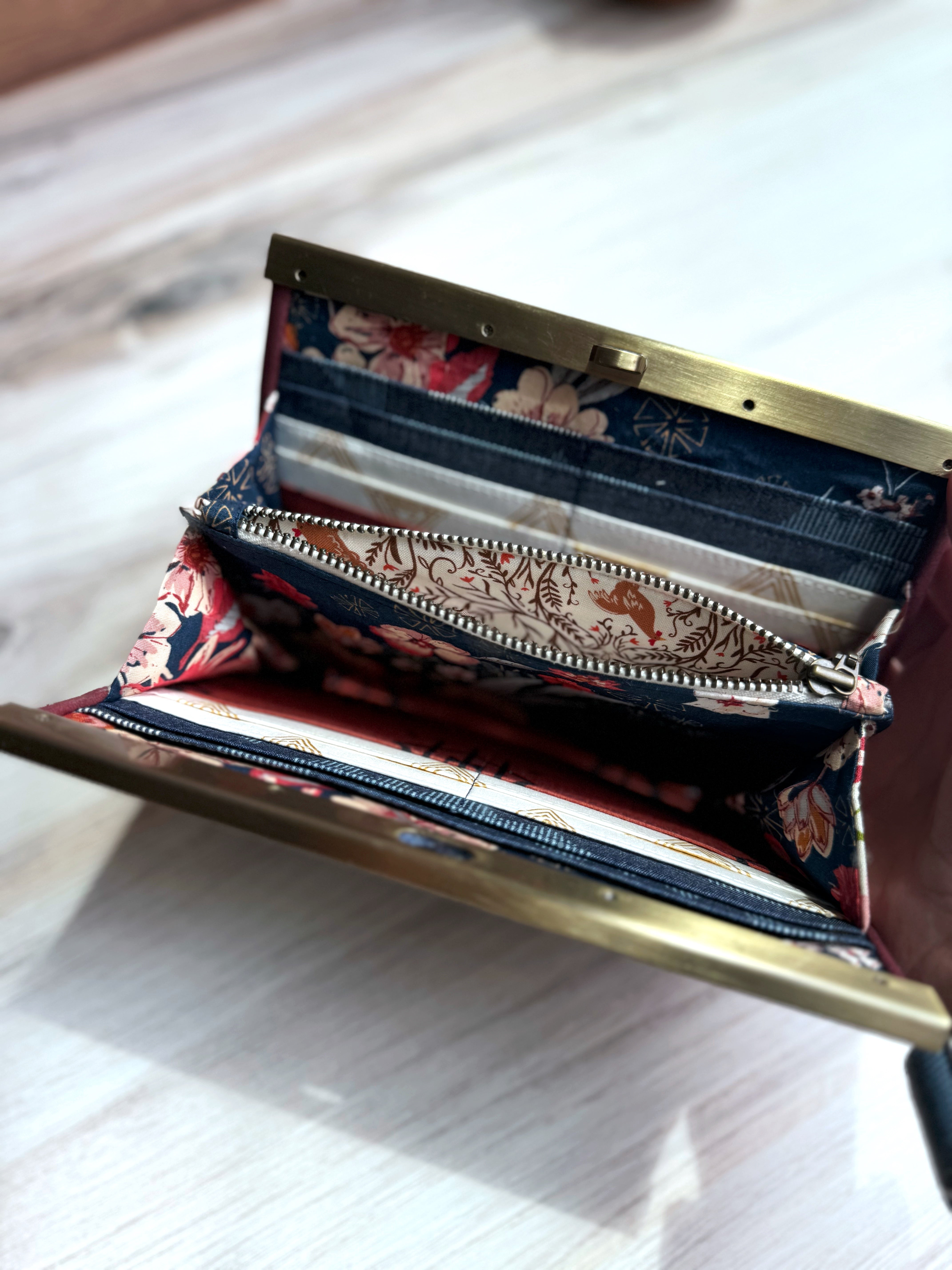 View of open accordion wallet in sun with many card and cash slots and open interior zipper pocket with rooster designs inside.