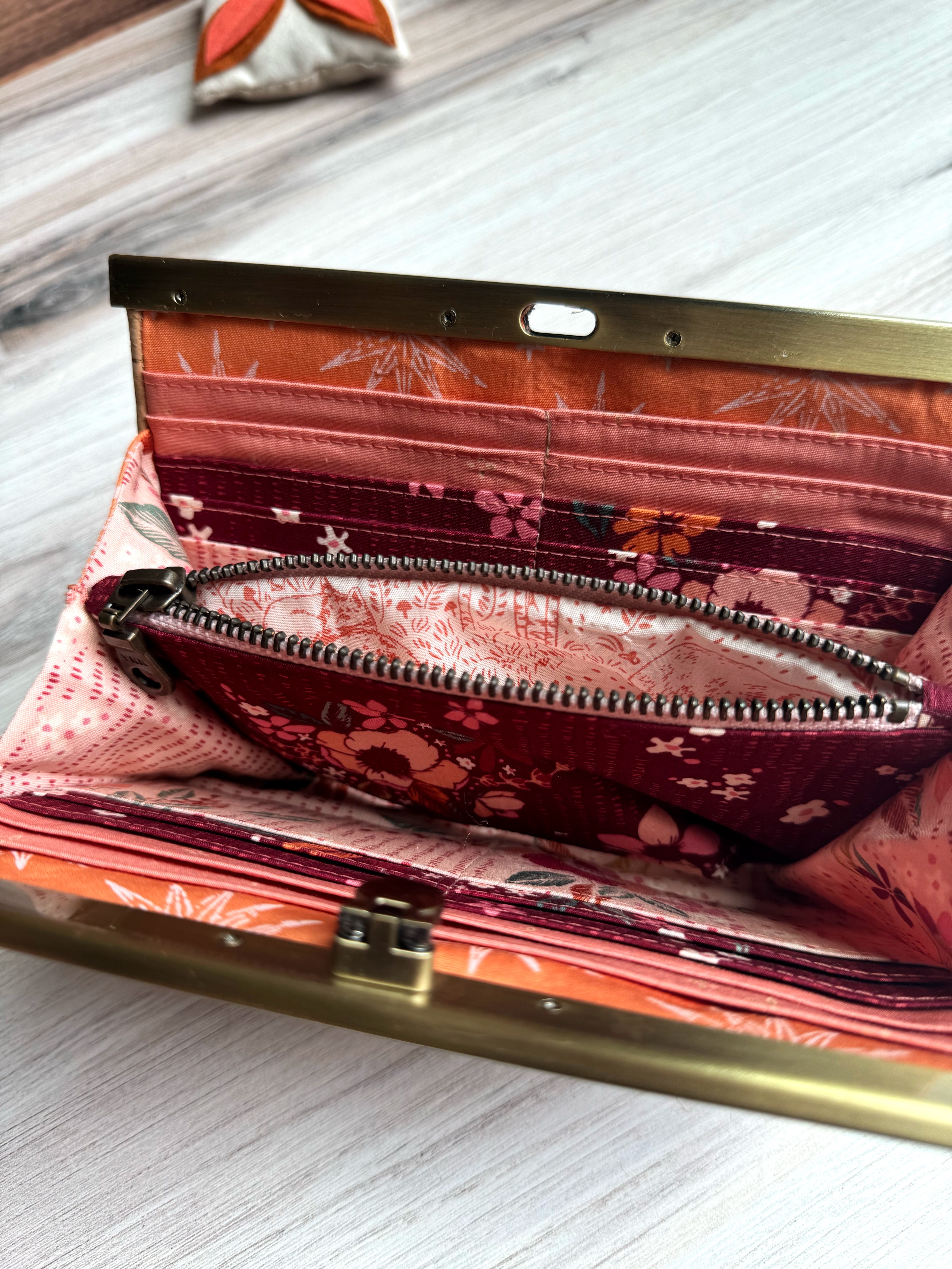 Open accordion wallet with pink, dark red, and orange interior fabrics with multiple card slots. Interior open zipper shows woodland animal fabric.