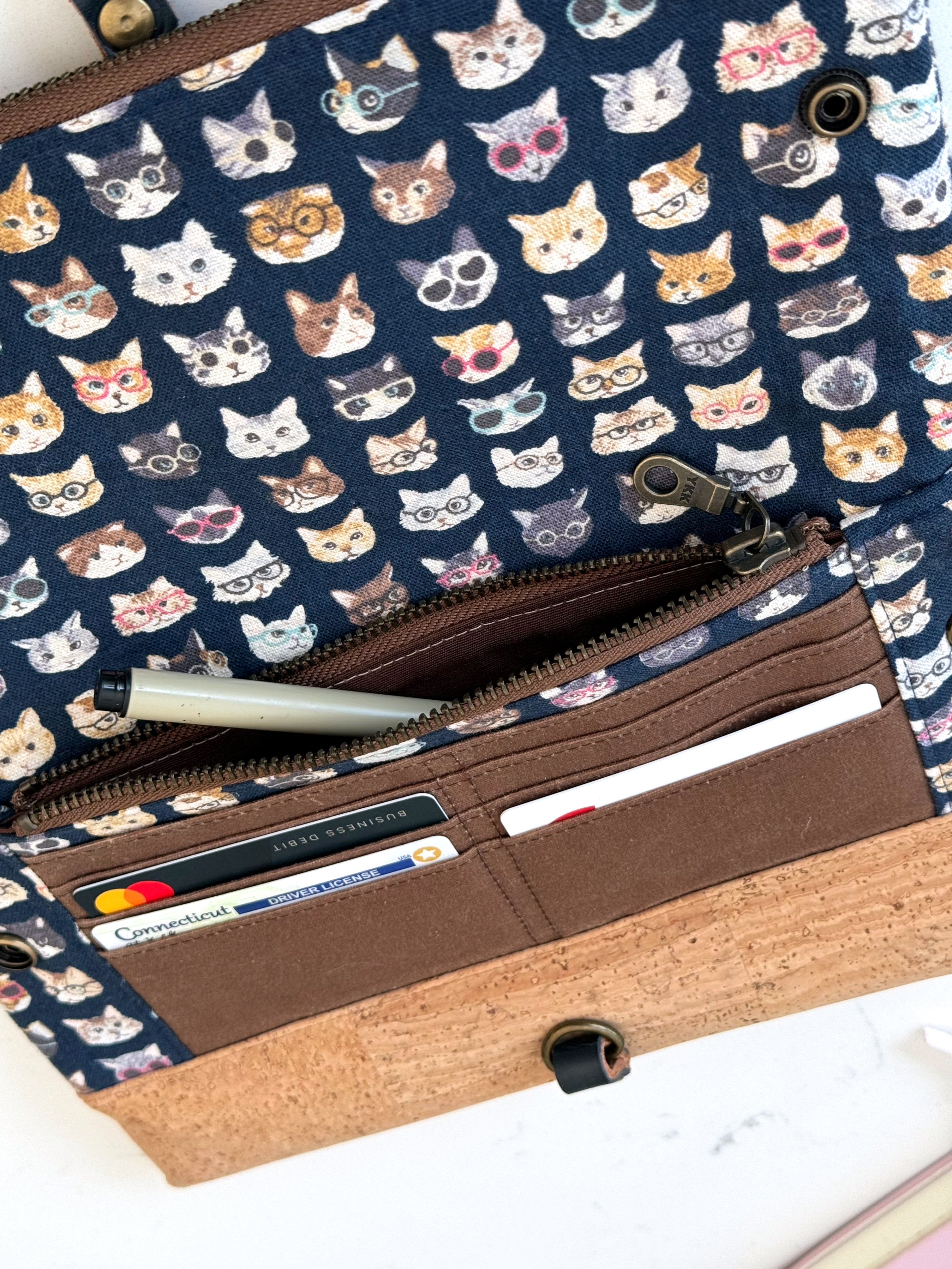 Opened clutch shows card slots with cards inside as well as open zipper pocket.  Also visible are heavy duty brass snaps.
