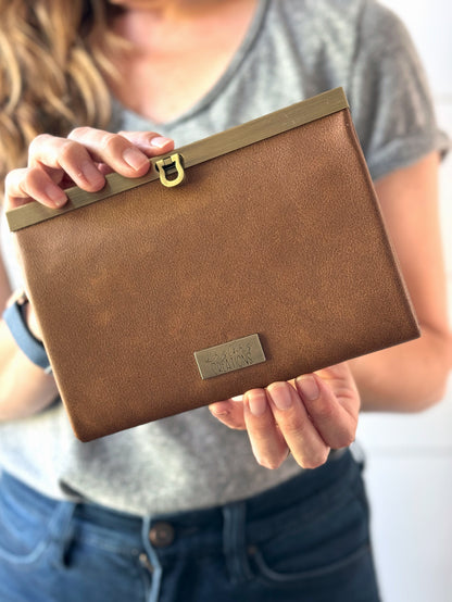 Tan Vinyl (vegan leather) accordion wallet, closed with antique brass hardware along top edge. Folds in compact rectangle.